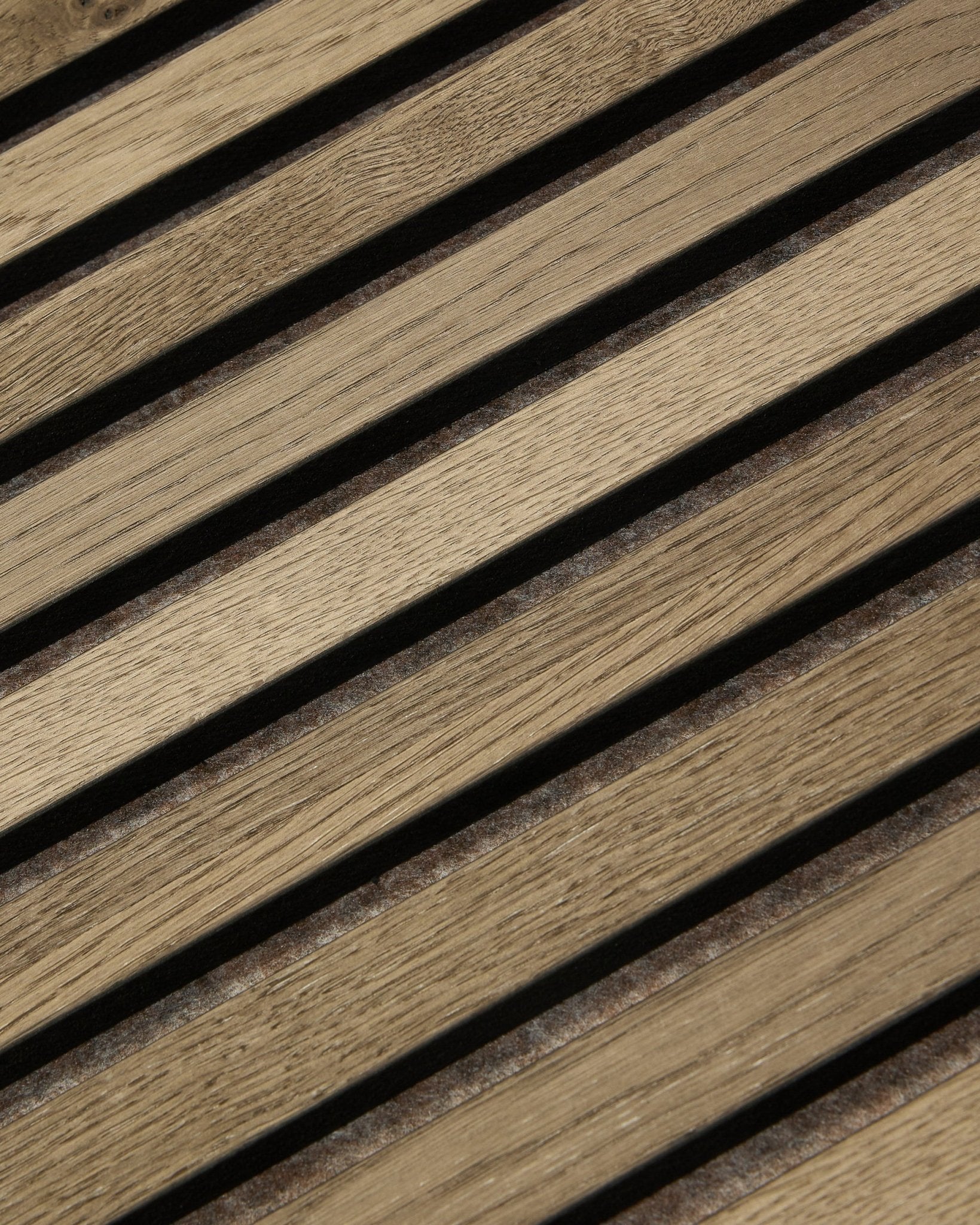 Gros plan sur le WoodUpp Tonal Akupanel Panneau acoustique en Grey Oak (240x60 cm), montrant des lattes diagonales régulièrement espacées, avec un veinage en natural oak et un design nordique.