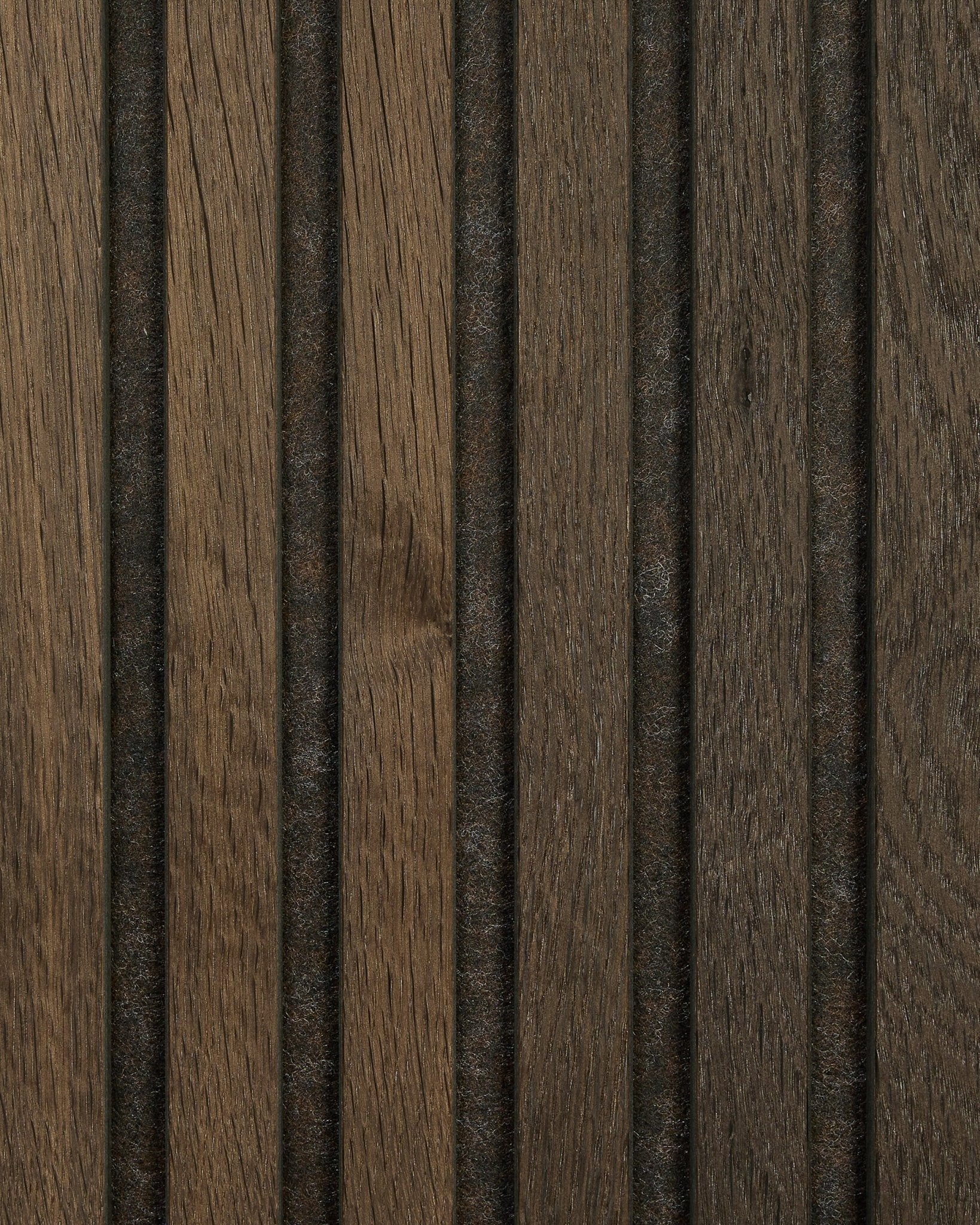 Gros plan sur un échantillon de panneau acoustique en bois Akupanel en Smoked Oak de WoodUpp, avec un veinage naturel brown, des rainures verticales et des lignes foncées régulièrement espacées.