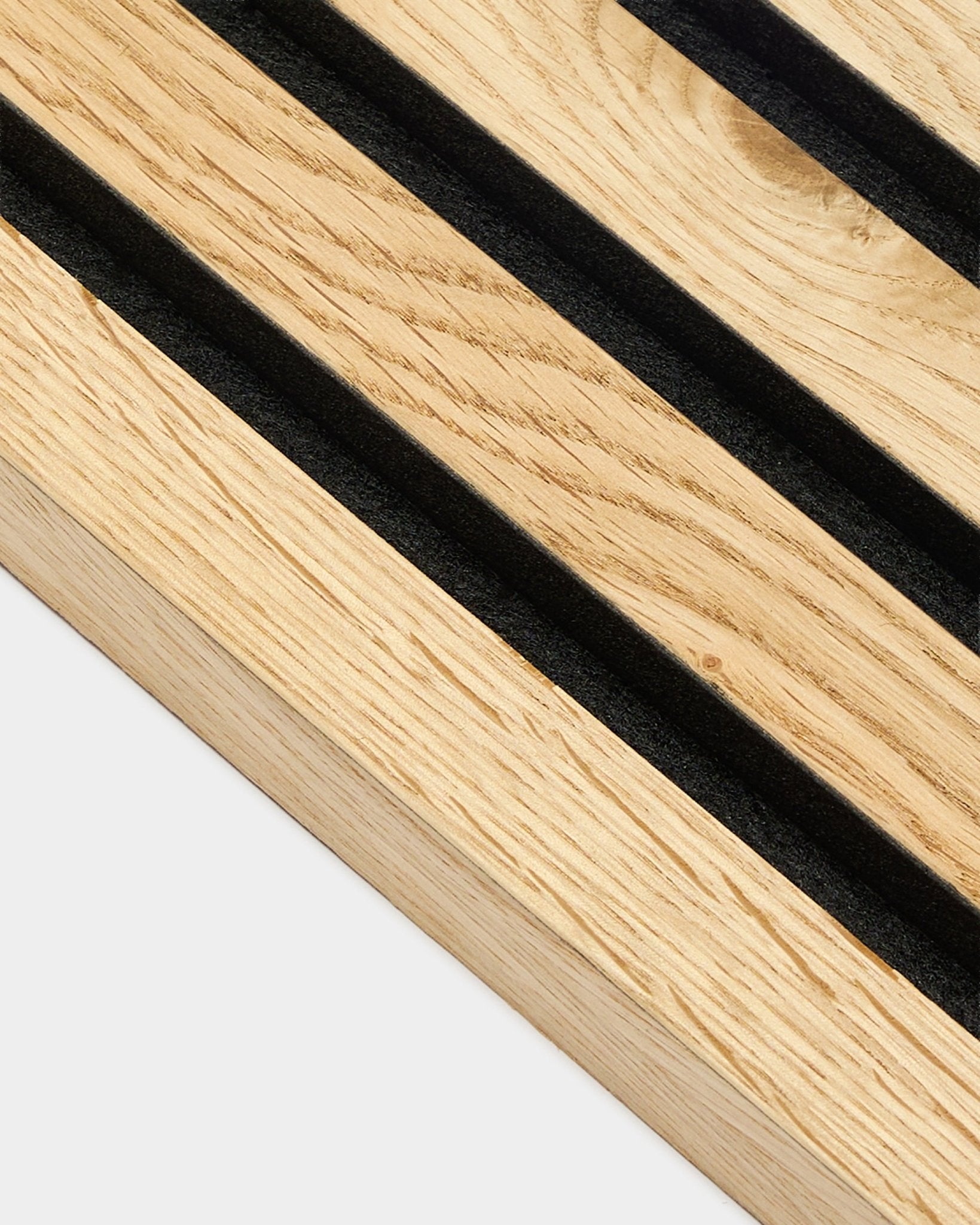 Gros plan sur la lamelle d’extrémité WoodUpp Akupanel en chêne rustique natural oak, d’une épaisseur de 2,2 cm, avec des rainures diagonales black et une texture de veinage en natural wood visible.