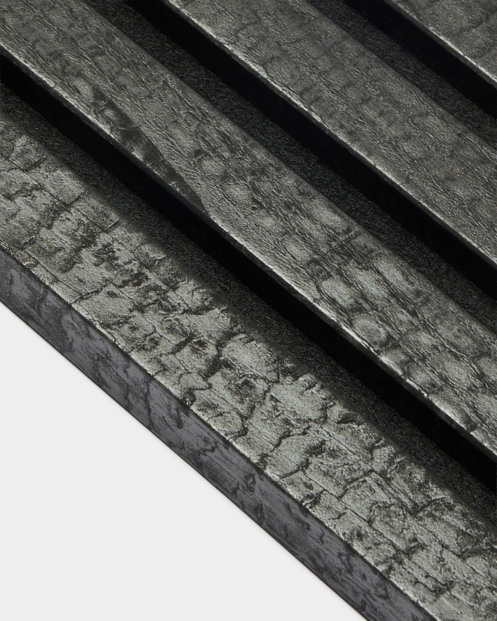 Lamelle de finition WoodUpp Akupanel en Charcoal (2,2 cm), avec des panneaux acoustiques en bois texturés et diagonaux, dans une finition black brûlée pour une installation murale.