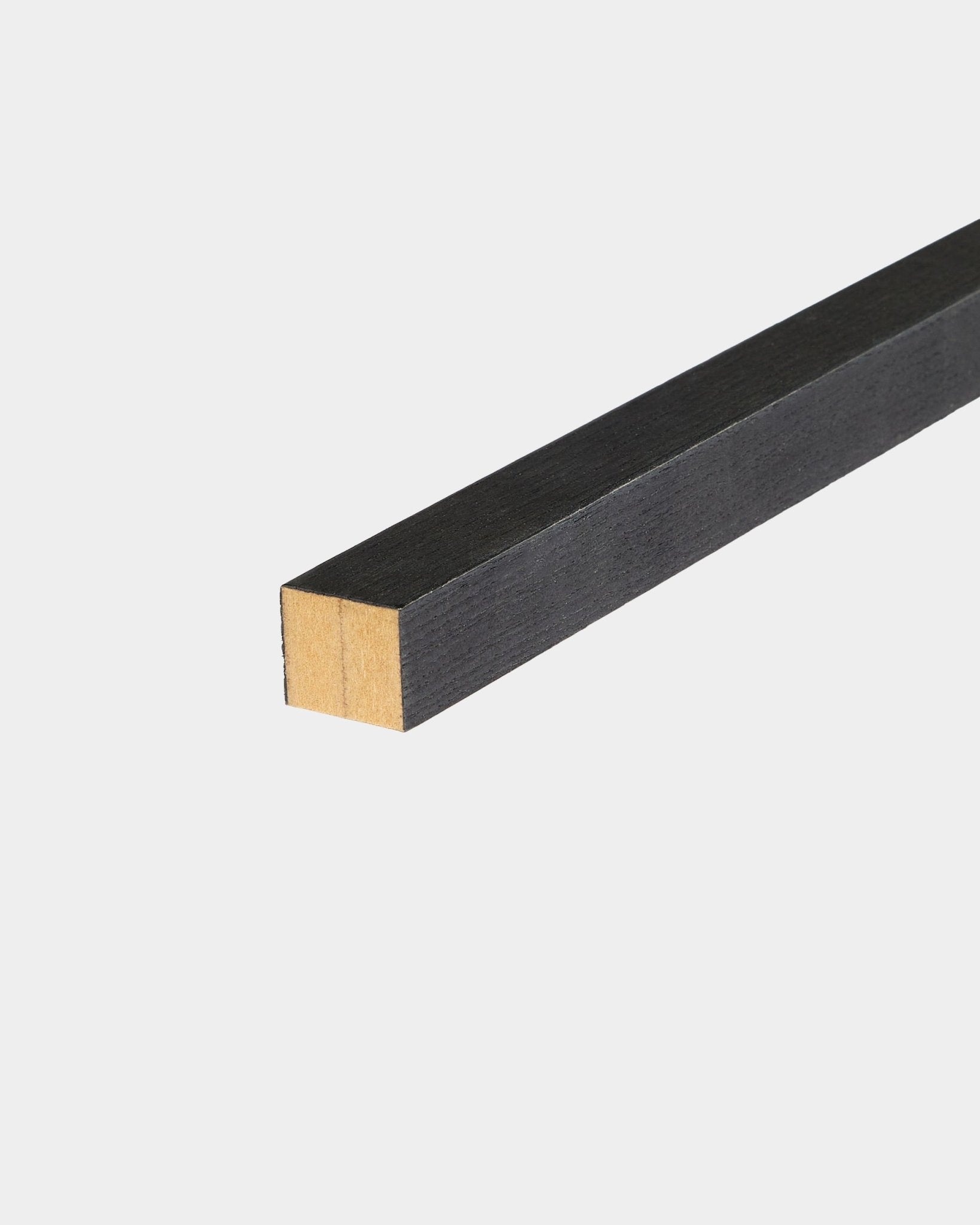 Lamelle d’extrémité WoodUpp en Black frêne, 2,2 cm, conçue pour l’installation de Akupanel Panneau acoustique, posée sur une surface blanche avec une extrémité non finie.