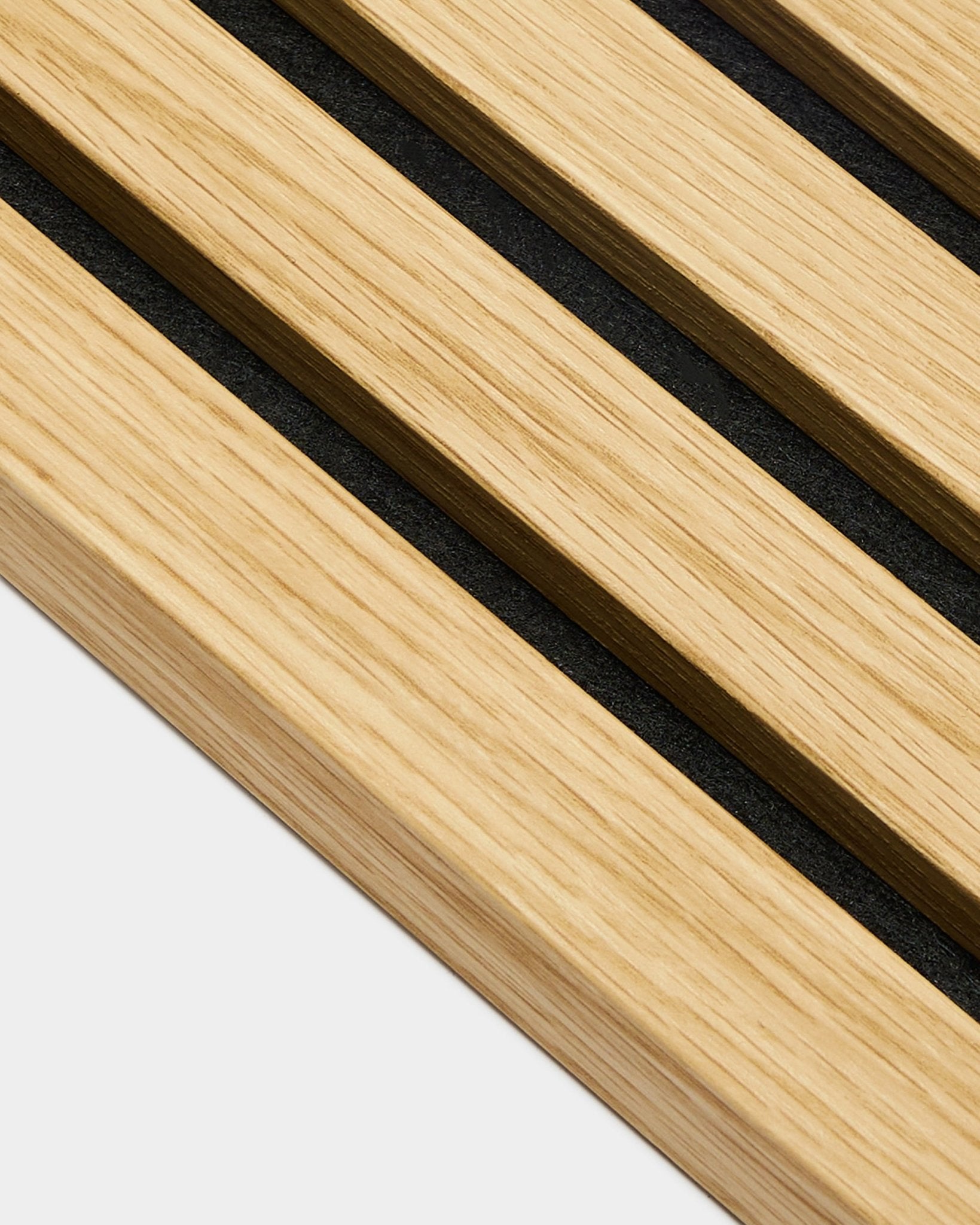 Gros plan sur la lamelle d’extrémité WoodUpp Akupanel en chêne Southern Oak, avec des lattes de 2,2 cm de large et des espaces black, disposée en diagonale sur un fond grey clair.