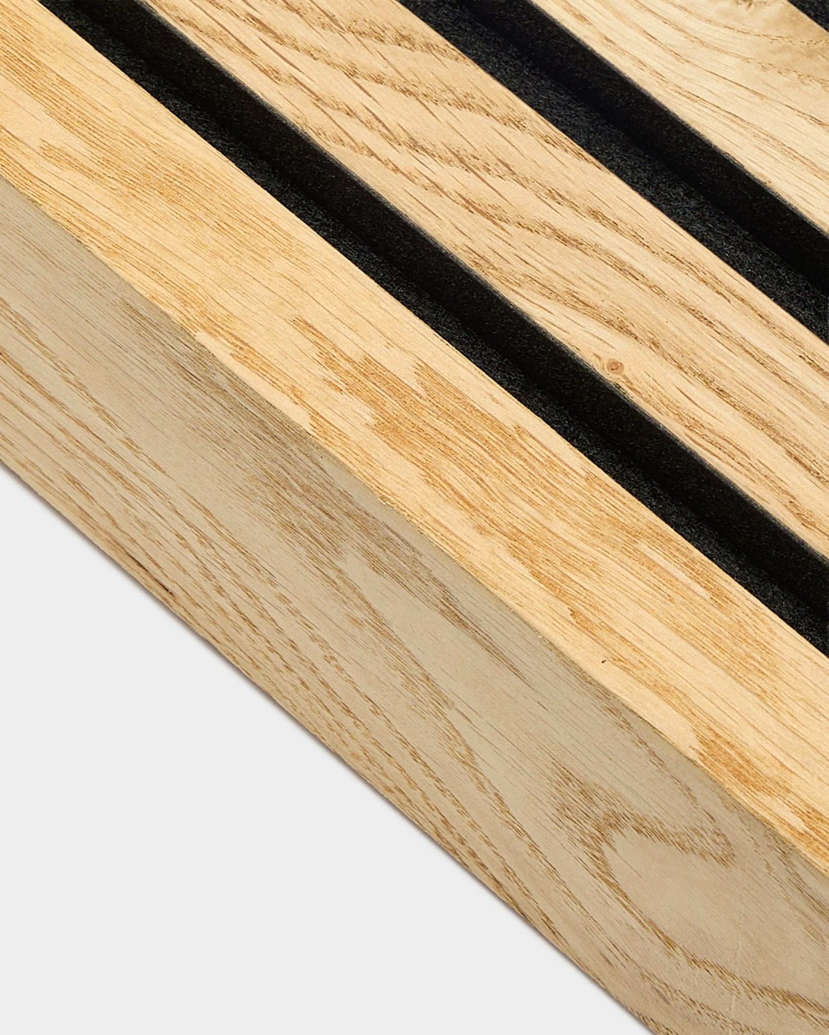 Gros plan sur une lamelle d’extrémité WoodUpp Akupanel en Rustic Natural Oak, 6,7 cm, avec des fentes parallèles black et un cadre MDF pour une installation murale acoustique.