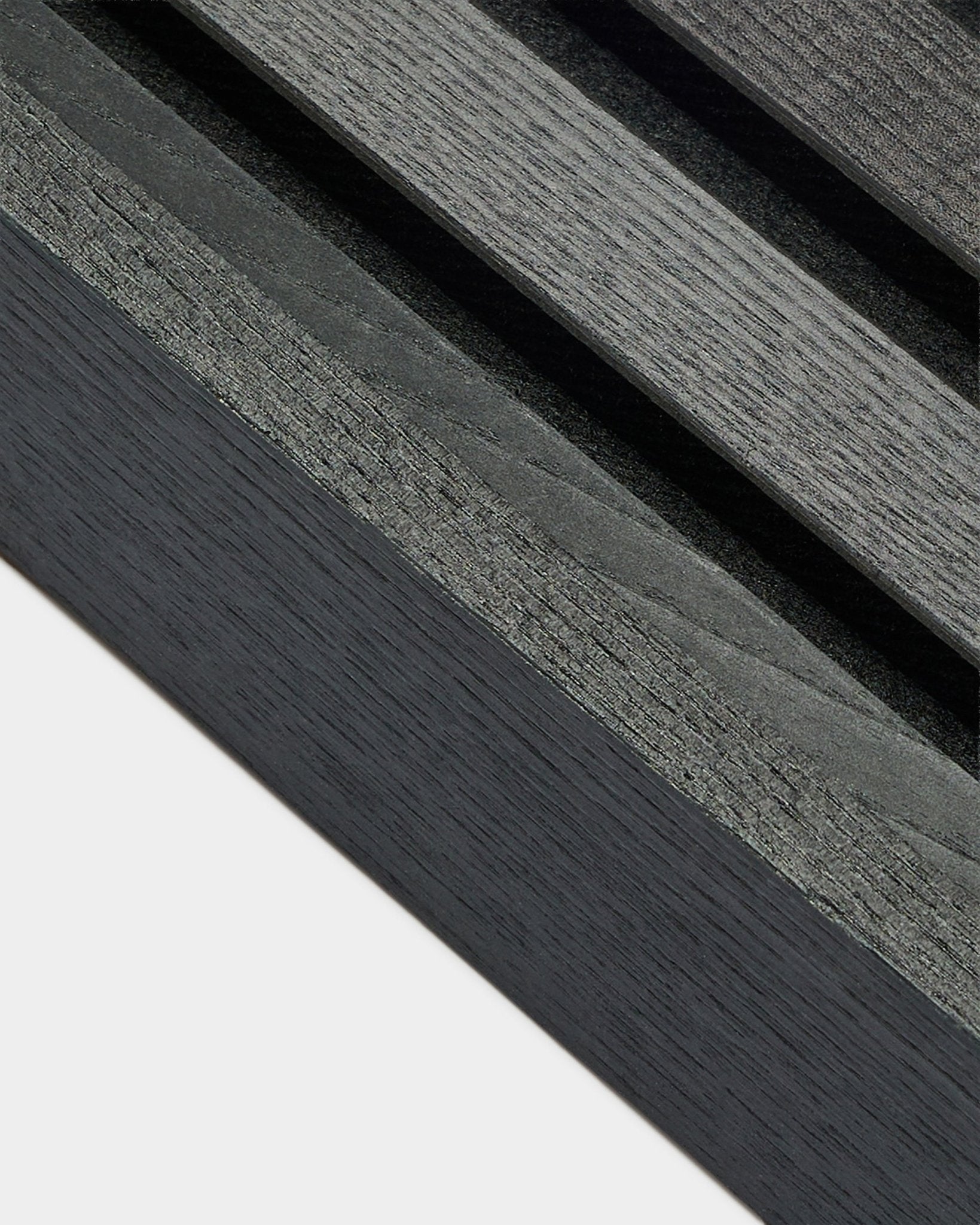Gros plan sur la lamelle d’extrémité WoodUpp Akupanel en Black Ash (6,7 cm), montrant un veinage gris foncé sur une base claire, conçue pour des installations nordiques de Panneau acoustique.