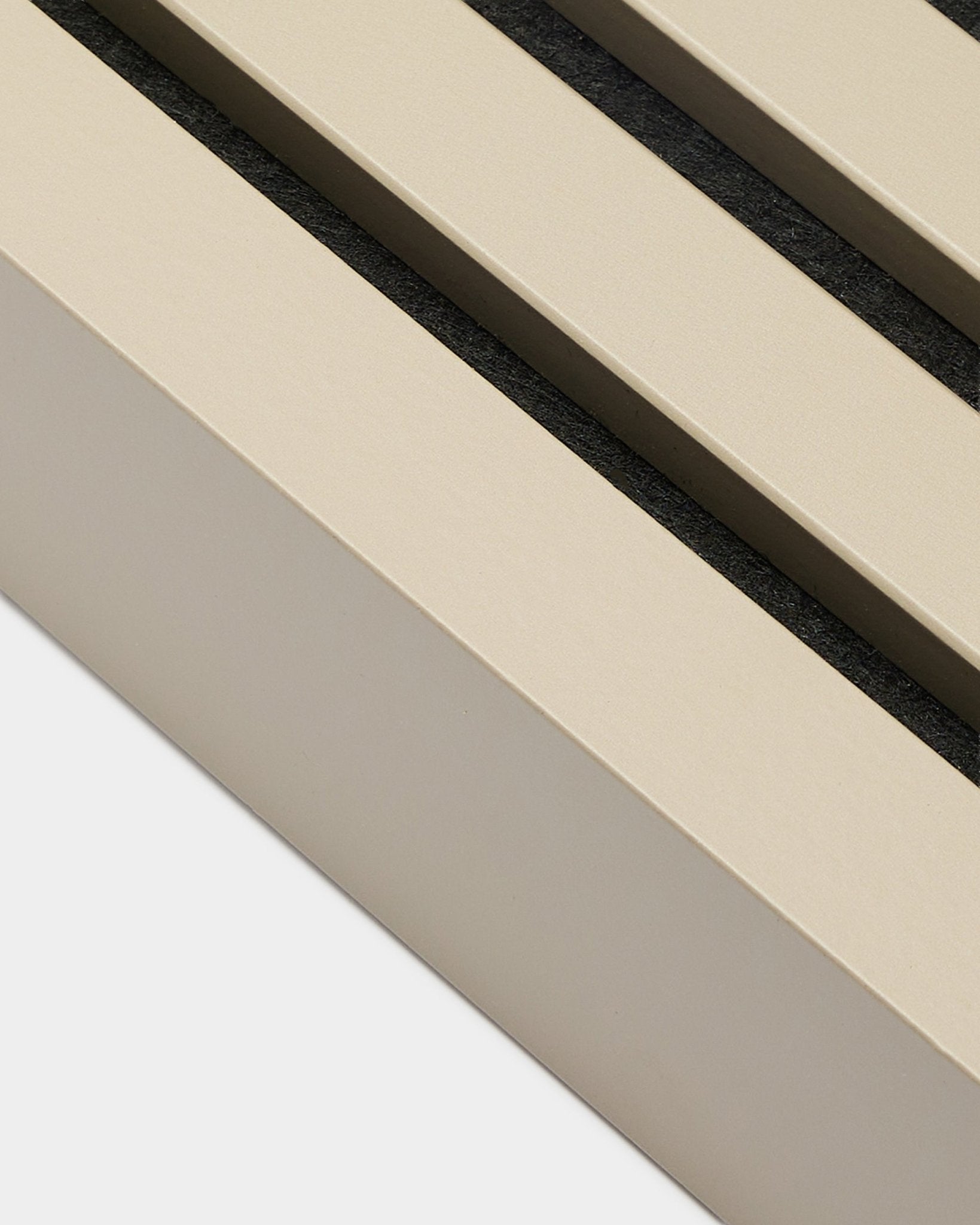 Gros plan sur WoodUpp End Lamella finition Stone, 6,7 cm de large — un accessoire d’installation pour les cadres en MDF ou les panneaux acoustiques Akupanel. Des lattes de panneau Beige avec des espaces black.