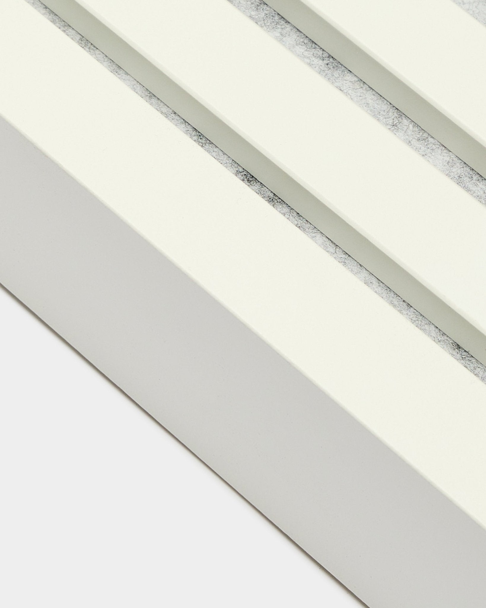 Gros plan sur la lamelle de finition WoodUpp en Snow, large de 6,7 cm, avec cadre en MDF, double rainure et finition texturée grey pour l’installation de Akupanel Panneau acoustique.