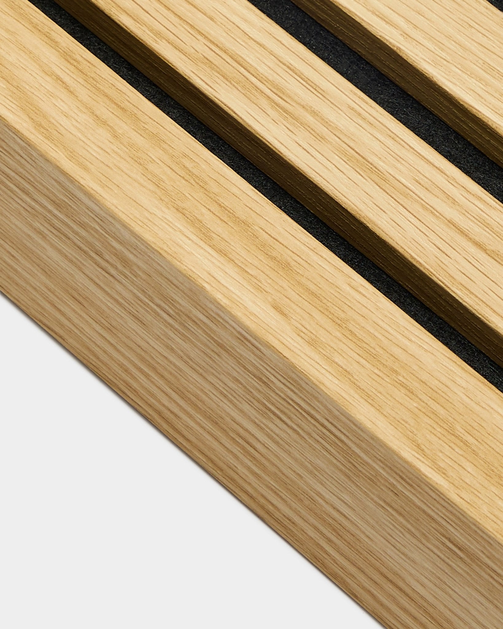 Gros plan sur un produit d’installation WoodUpp Akupanel, une lamelle d’extrémité en chêne du Sud de 6,7 cm de large, avec des rainures black sur bois clair pour des lignes de Panneau acoustique bien définies.