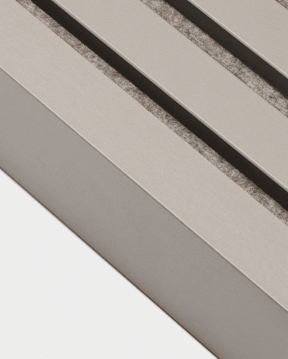 Nahaufnahme einer WoodUpp Akupanel-Endlamelle in der Farbe „Dark Cashmere“, 240 × 6,7 cm, mit Schatten der Lüftungsschlitze auf einem beigen MDF-Rahmen.