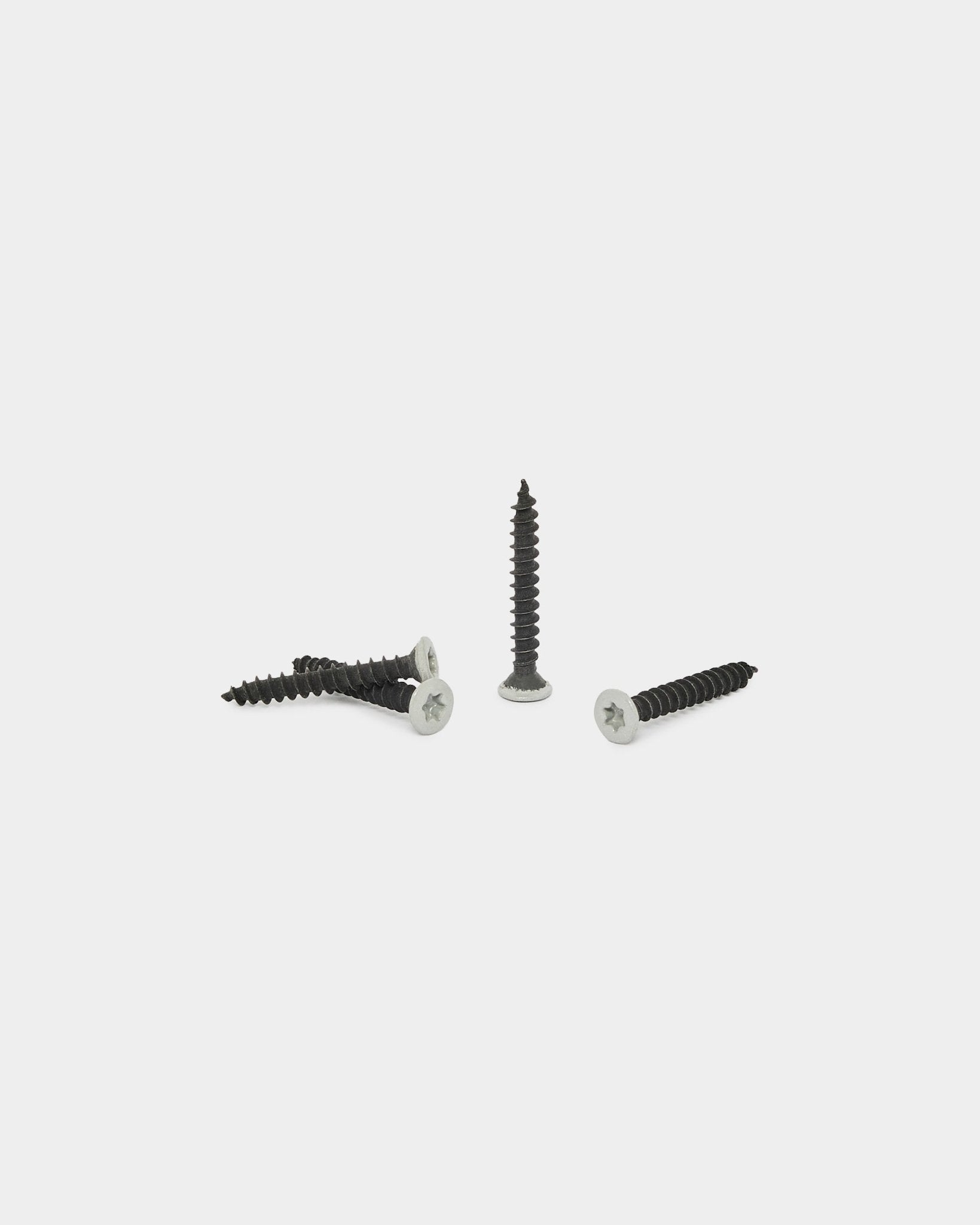 Quatre vis WoodUpp grey du kit Produits d’installation (100 pcs), présentées sur un fond blanc uni ; trois sont à l’horizontale et une est debout.