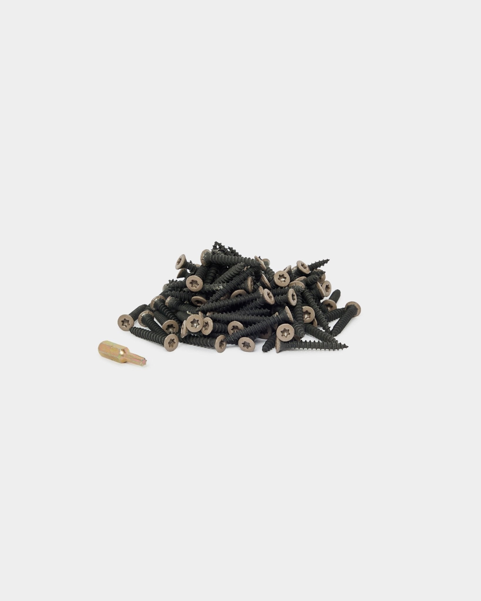 Vis de montage WoodUpp Warm Grey (100 pcs) et un embout de tournevis doré disposés sur un fond blanc, adaptés à l’installation d’un Panneau acoustique ou d’un accessoire de panneau.