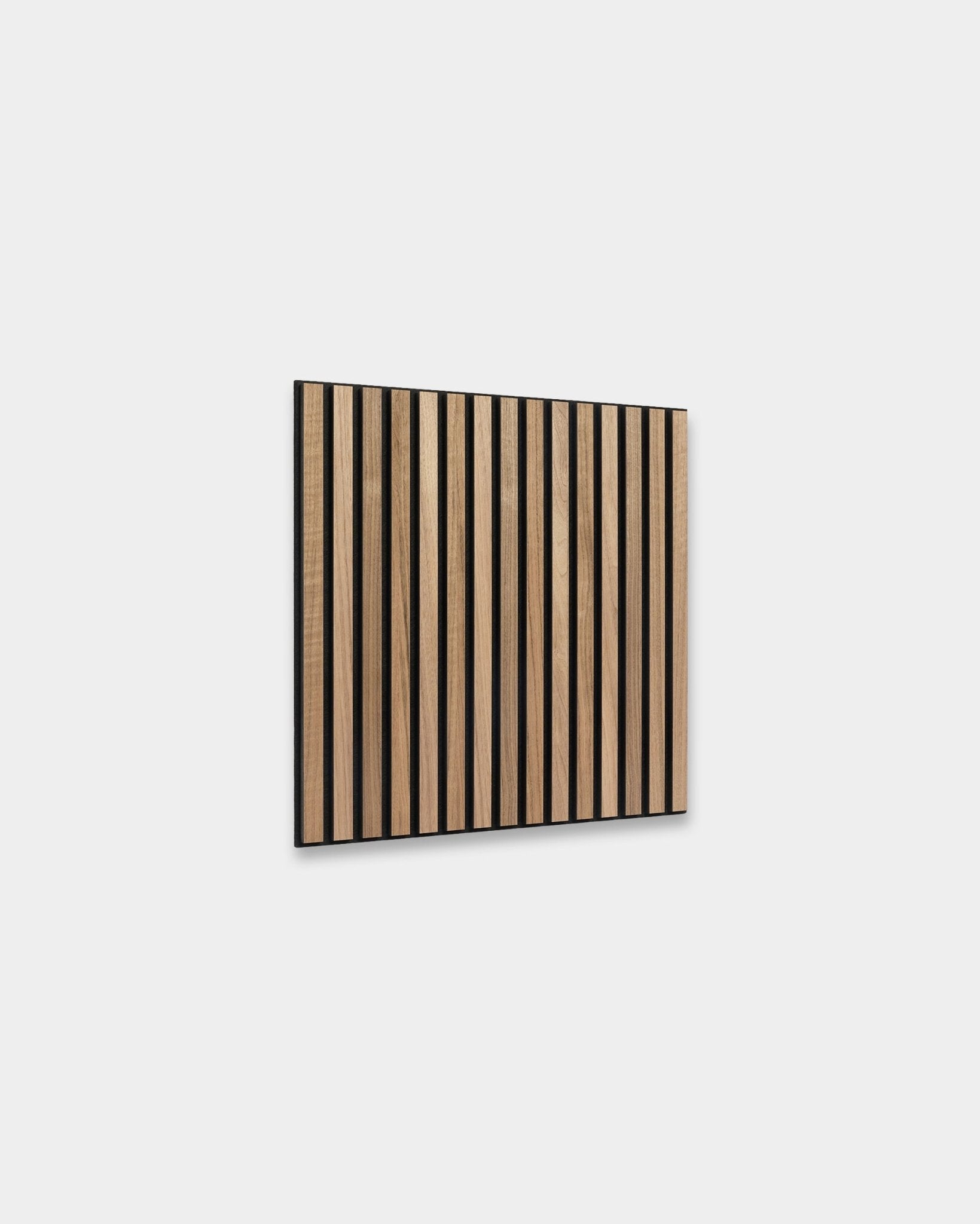 Le Akupixel Panneau acoustique WoodUpp en noyer, 60 x 60 cm, présente des lattes en noyer régulièrement espacées avec des interstices black, monté sur un mur gris clair dans un style scandinave.