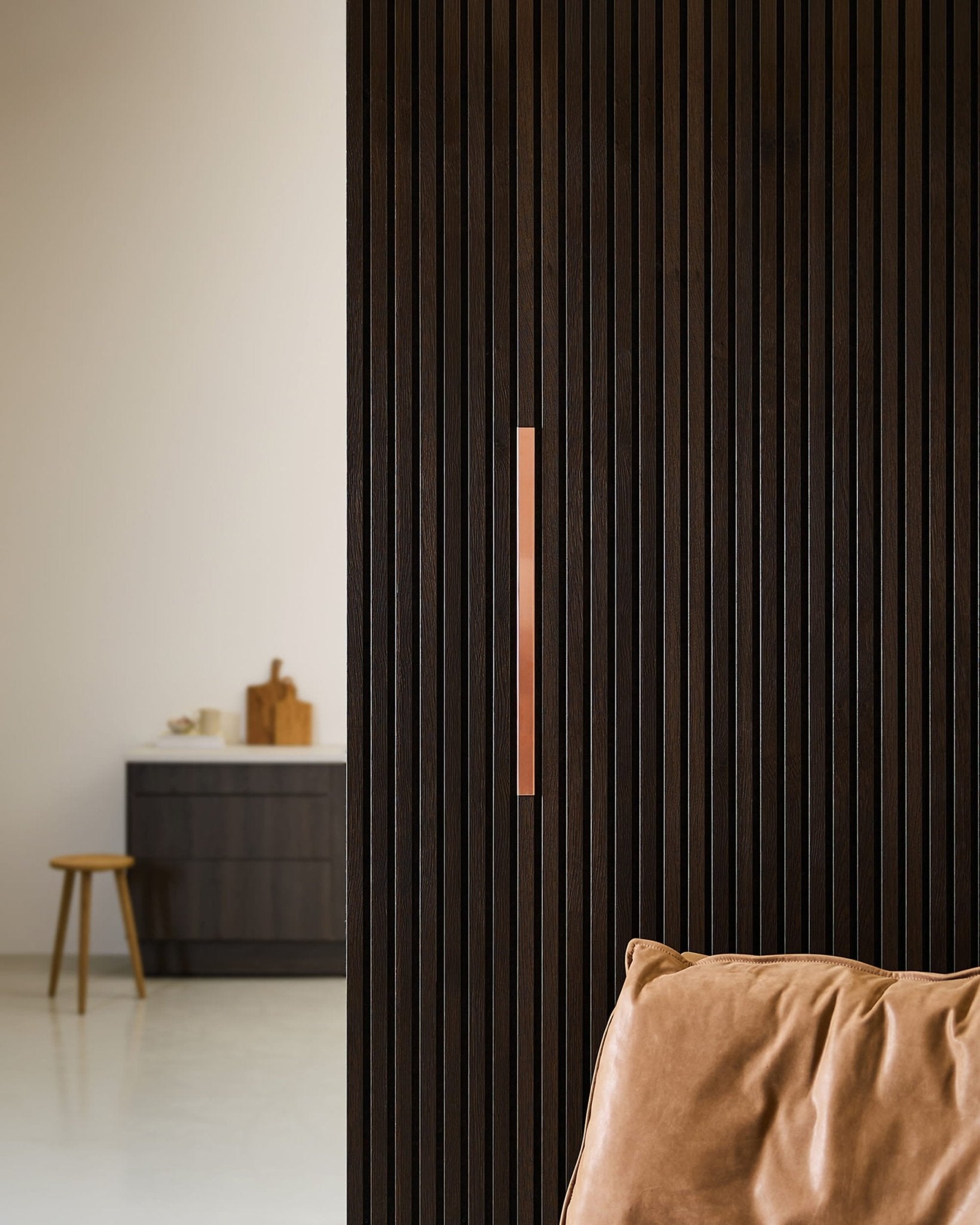 Minimalistische Küche mit einem WoodUpp Liva | Verkleidung / Akustikpaneel in Kupfer an einer 60 cm breiten Wand, Stuhl aus hellbraunem Leder, Hocker und Arbeitsplatte.