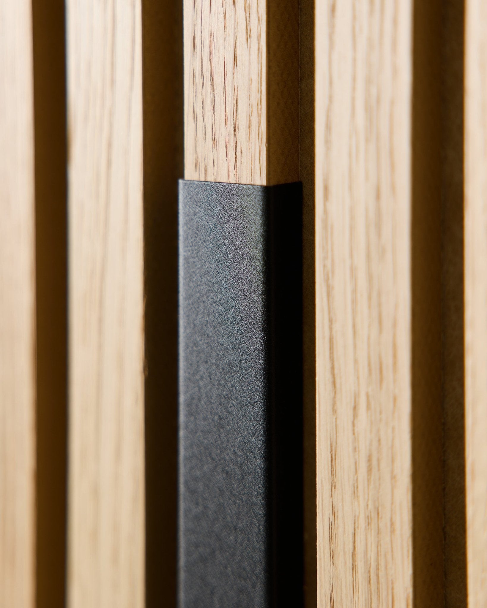 Gros plan sur le panneau acoustique WoodUpp Liva avec cache en aluminium black de 60 cm, mettant en valeur des lattes de bois verticales et un accent black pour des intérieurs modernes et nordiques.