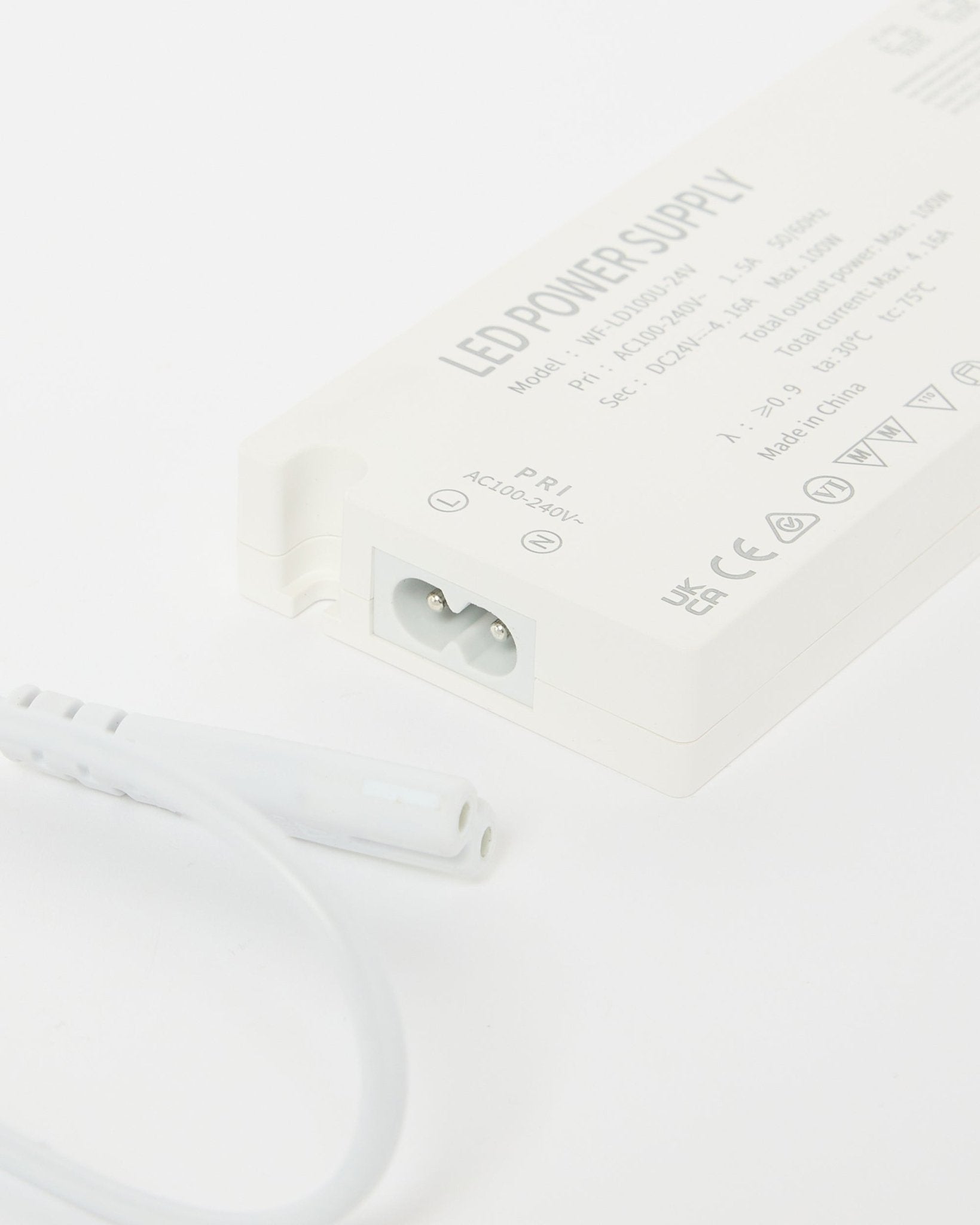 Nahaufnahme eines beigeen WoodUpp Lumi Netzteils für LED-Lichtleisten (240 cm) mit technischen Details und einem danebenliegenden Kabel, entwickelt für nordische Akustikpaneel-Installationen.