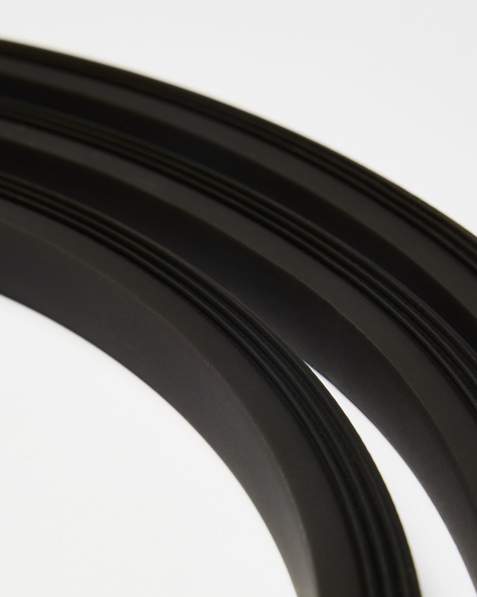 Nahaufnahme der blacken Lumi LED-Lichtleiste von WoodUpp (300 cm), in geschwungenen Linien auf Weiß arrangiert, als Ergänzung zum minimalistischen Akupanel Akustikpaneel-Stil.
