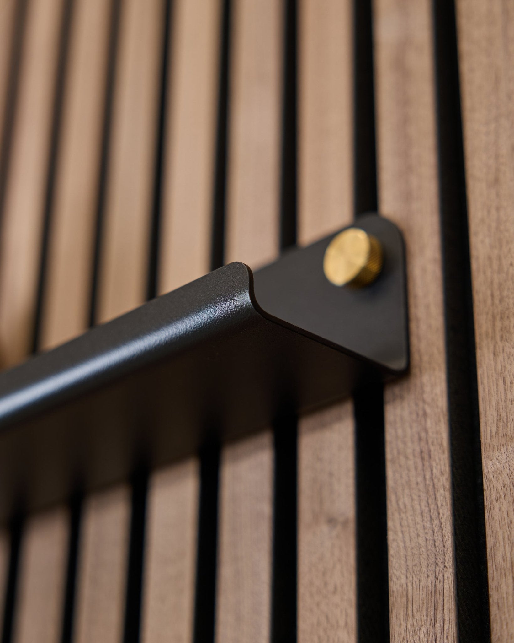 Nahaufnahme des WoodUpp Norr | Narrow Shelf (75,9 cm) in black, mit einem Griff aus steel, goldfarbenen Bolzen und einer vertikal gerillten Akustikoberfläche.