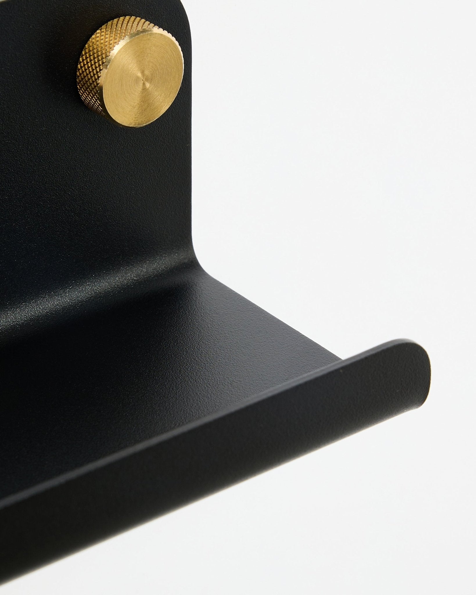 Nahaufnahme der WoodUpp Norr Schmale Ablage in black, 75,9 cm, mit einem strukturierten goldfarbenen Knauf, vor weißem Hintergrund.