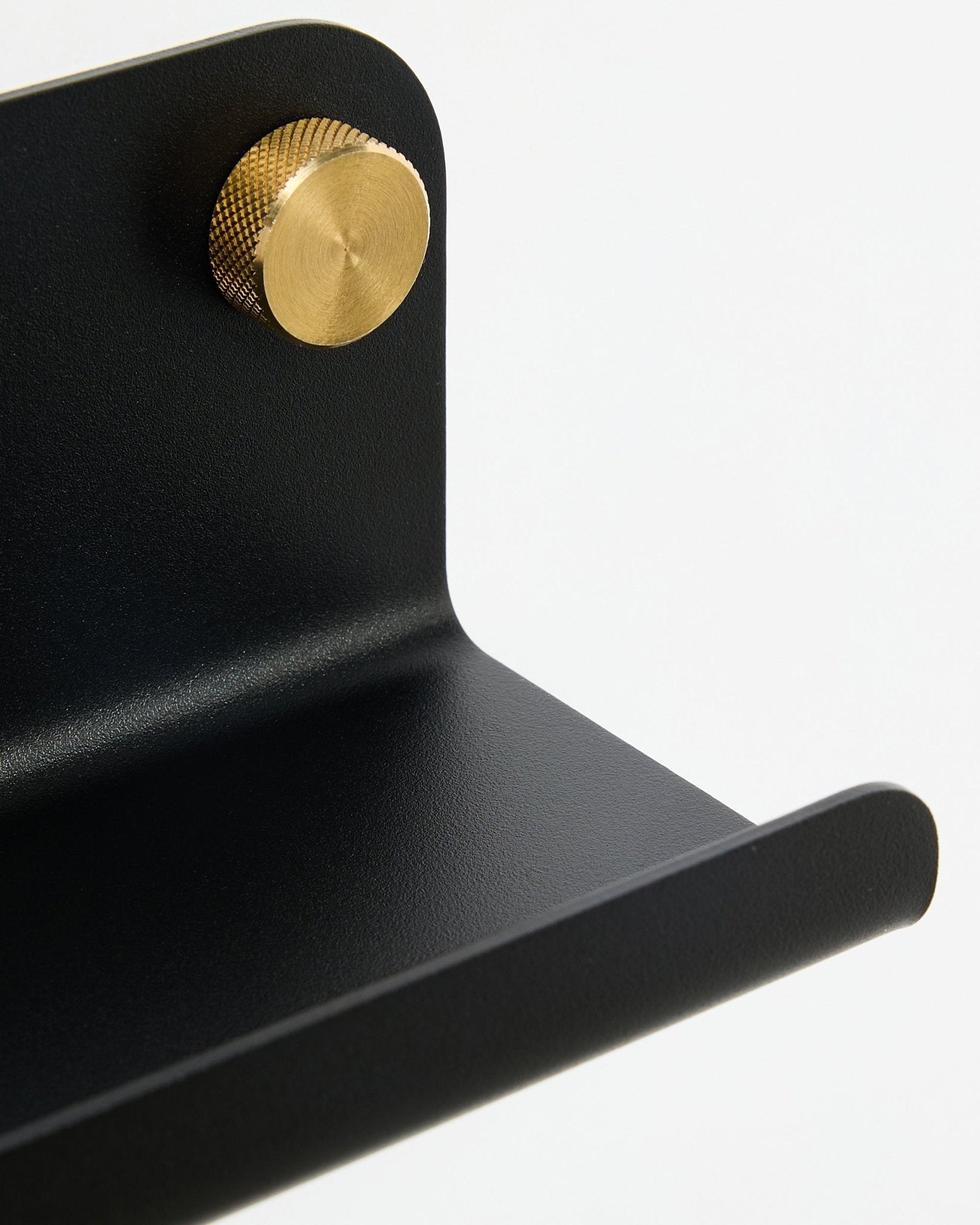 Gros plan sur l’étagère étroite WoodUpp Norr Narrow Shelf, 35,9 cm, en black steel avec bord incurvé et bouton doré, sur fond blanc.