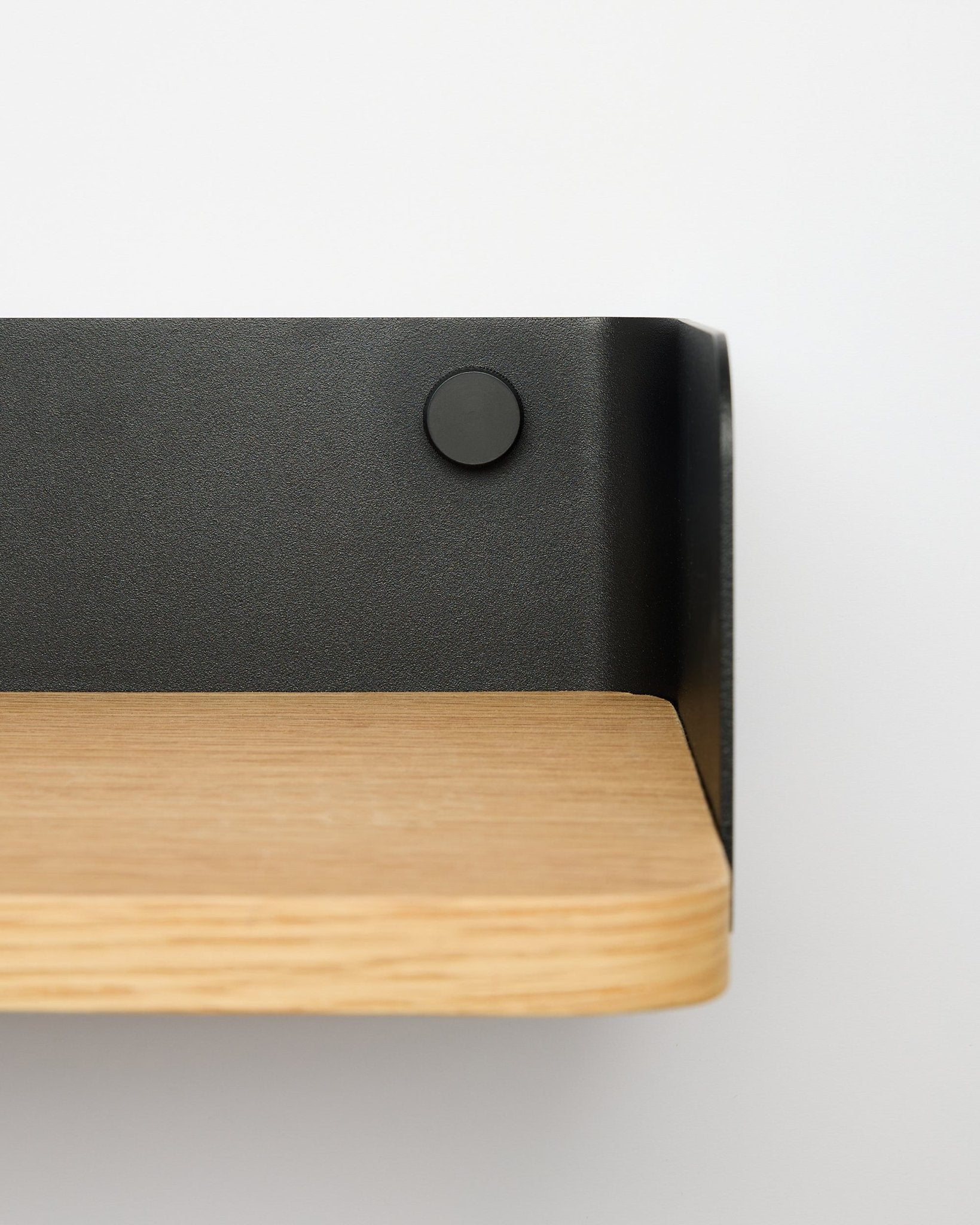 Bibliothèque Linn Bookshelf de WoodUpp en natural oak, largeur 55,9 cm, avec support métallique black, fixée sur un mur blanc ; vue rapprochée depuis le côté droit.