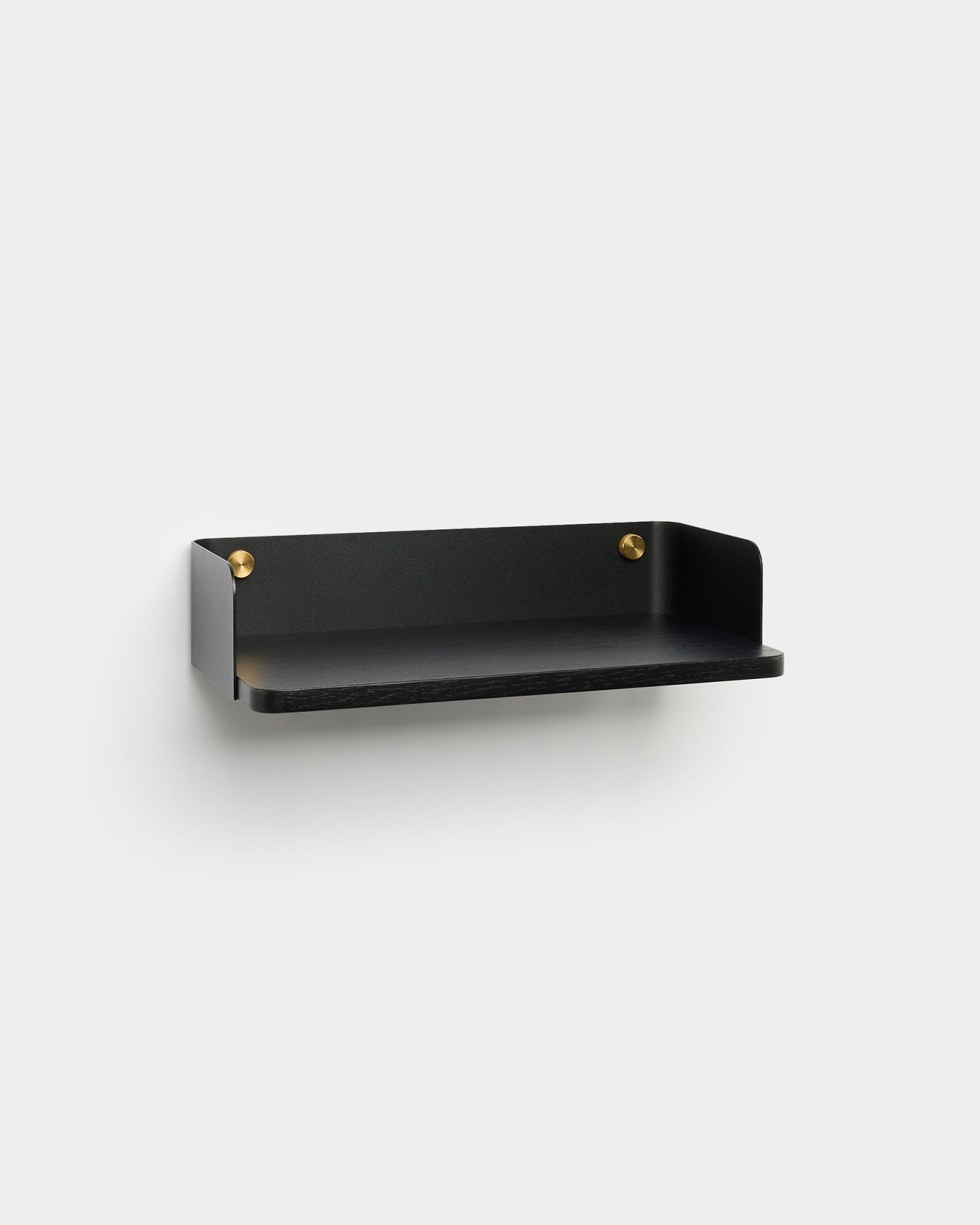 L’étagère Linn de WoodUpp, dans une finition minimaliste black avec des vis de fixation en brass, est installée sur un mur gris clair et complète un intérieur nordique.