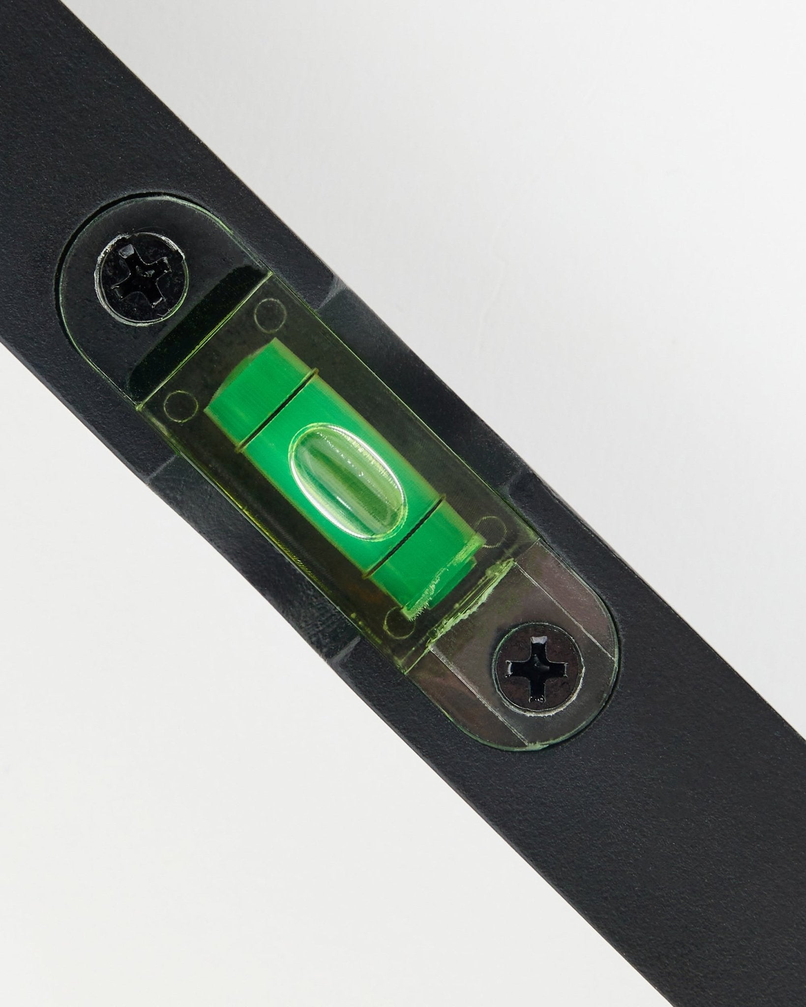Gros plan sur un niveau à bulle WoodUpp black (15 x 3,2 cm) avec fiole verte, utilisé pour la pose précise de panneaux acoustiques.