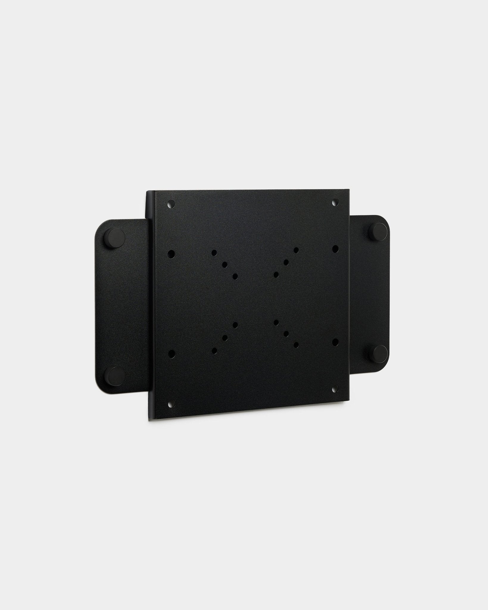 Le Fjell | TV Mount (small) de WoodUpp, un support métallique black avec plusieurs trous de vis et un verrou magnétique, présenté sur fond blanc.