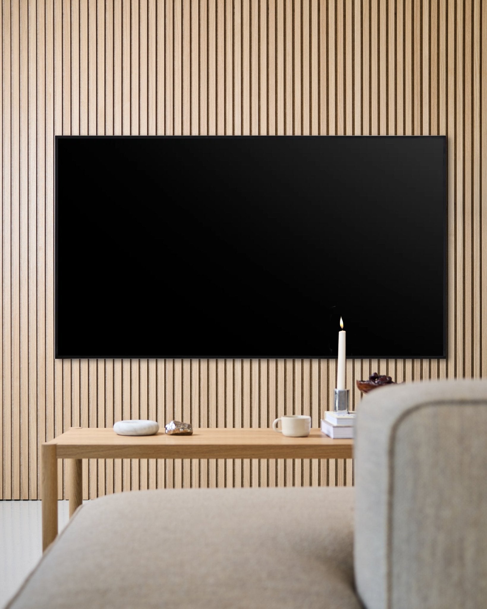 Salon moderne avec un téléviseur à écran plat fixé au mur, un mur acoustique en lattes de bois Akupanel et une table basse en bois pour une ambiance chaleureuse.
