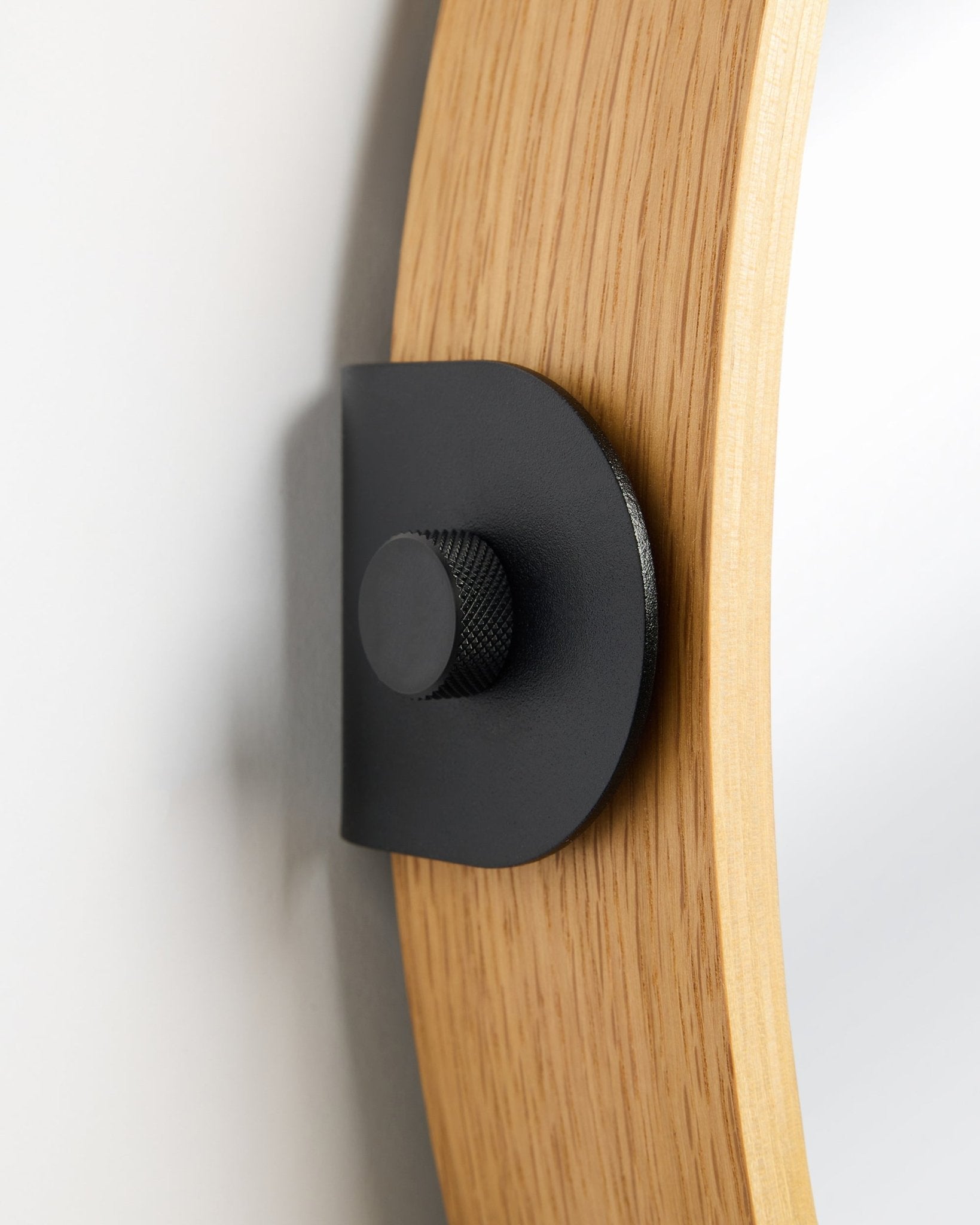 Détail du miroir WoodUpp Linn en Natural Oak, un Panneau acoustique fixé au mur avec un support métallique black et un bouton rond.