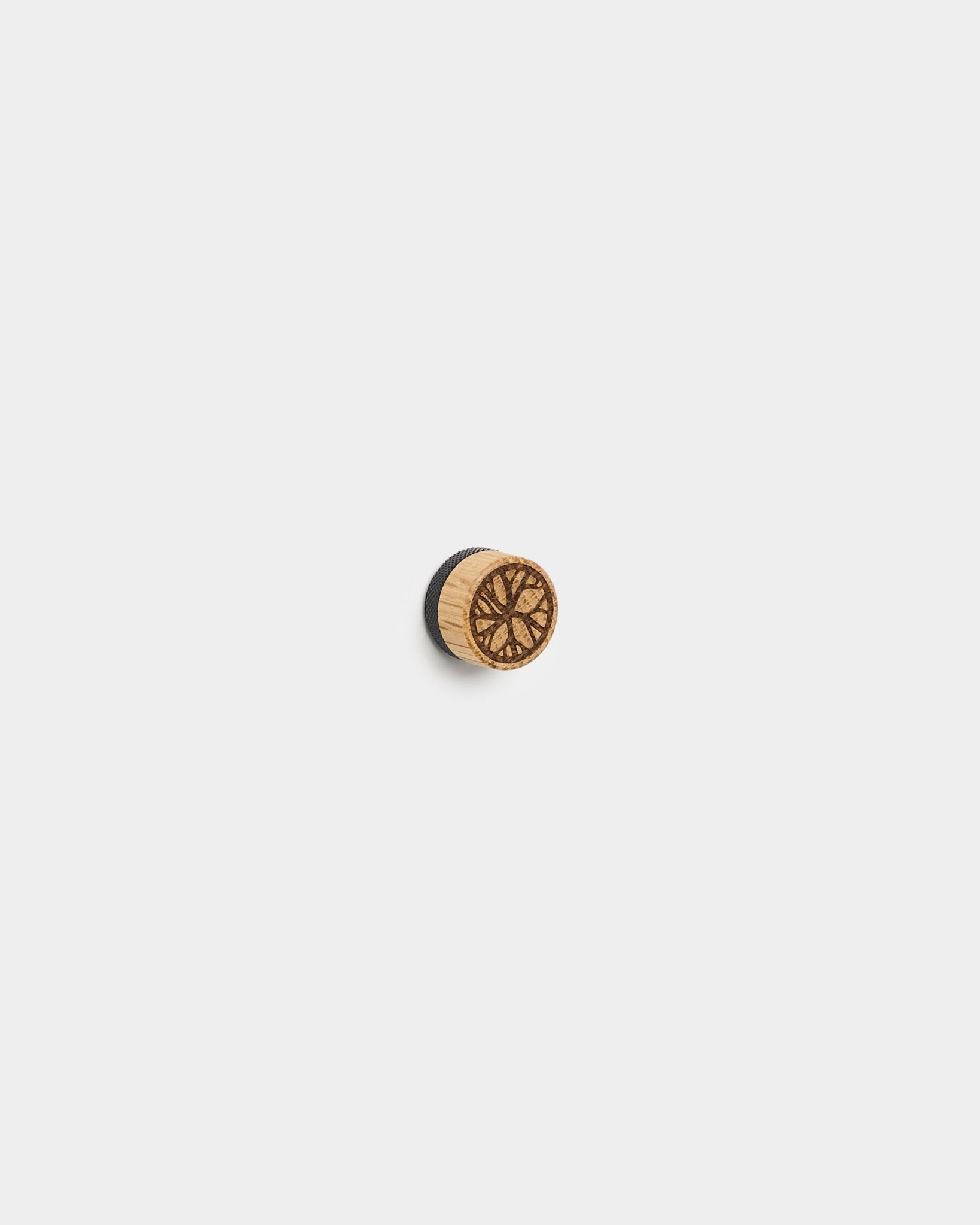 Le set de magnets pour affiches Norr de WoodUpp comprend de small boutons ronds en chêne au motif géométrique, conçus pour afficher des photos sur des panneaux acoustiques blancs ou des panneaux à lattes.