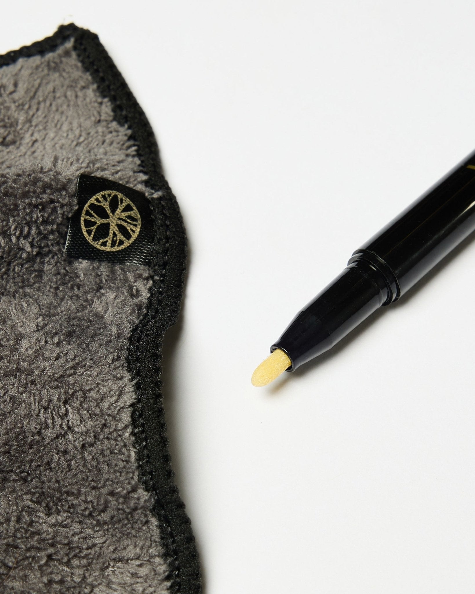 Das Norr Blackboard-Set von WoodUpp enthält einen blacken Kreidemarker mit gelber Spitze und ein graues Mikrofasertuch mit goldenem Etikett, gezeigt auf einer weißen Oberfläche.