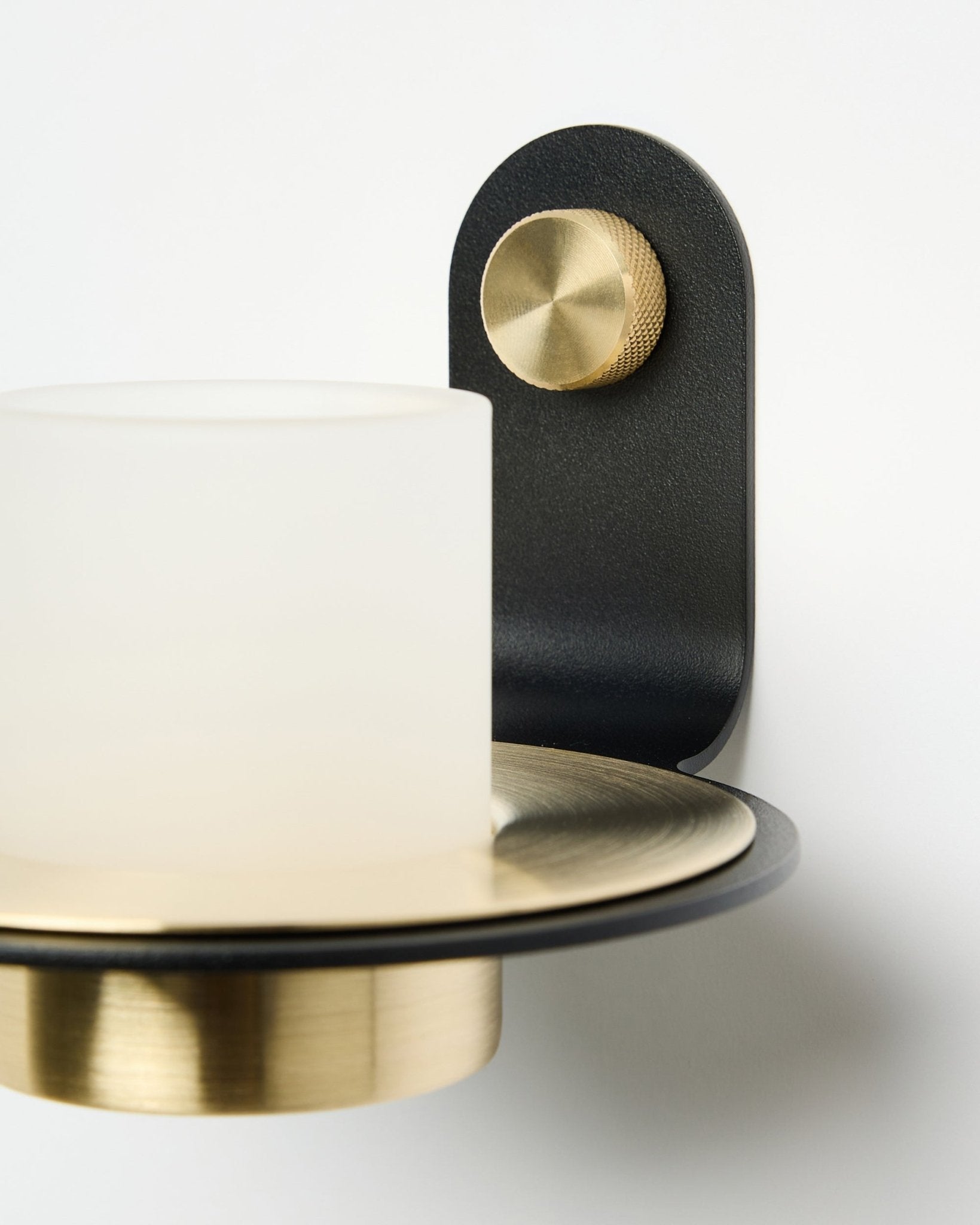 Der Norr Kerzenhalter von WoodUpp in black und brass, hier mit LED-Kerzen auf einem weißen Akustikpaneel montiert.