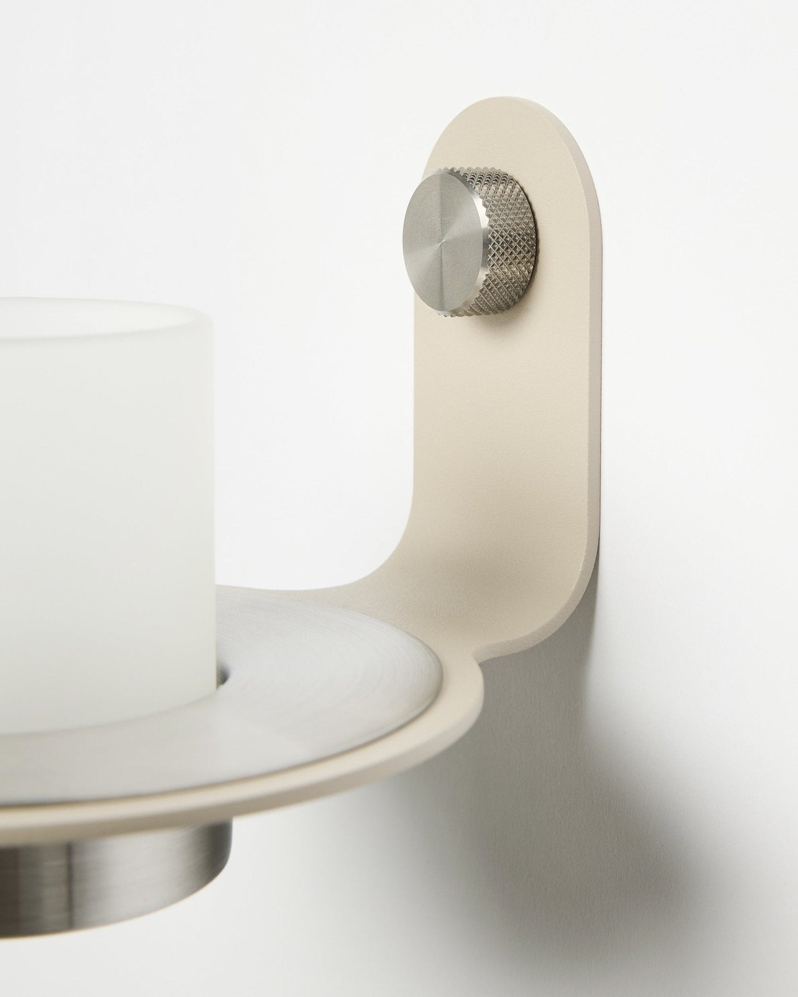Le bougeoir minimaliste Norr en beige et steel inoxydable de WoodUpp, présenté comme accessoire pour les panneaux muraux acoustiques à lattes Akupanel.