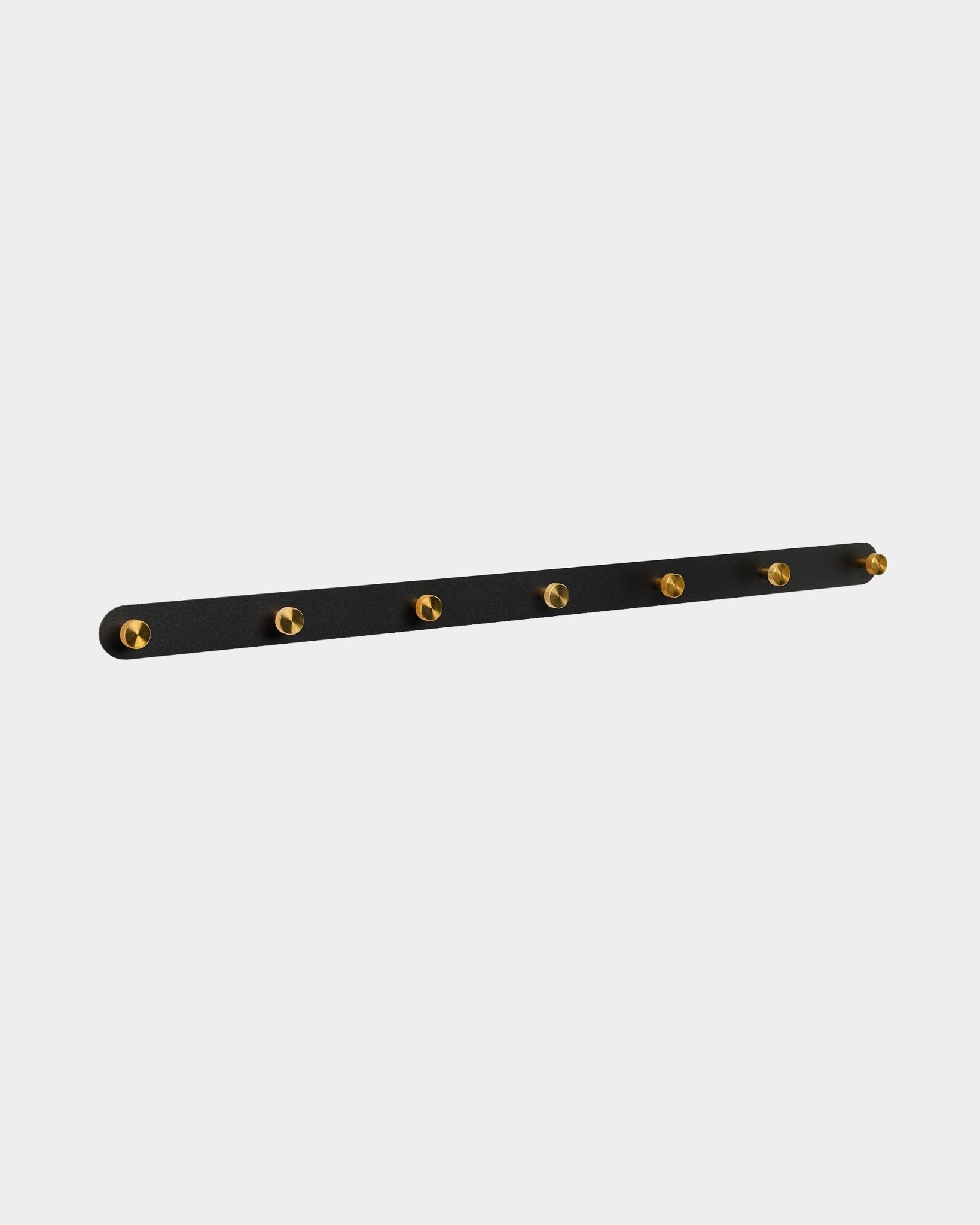Patère Norr de WoodUpp avec 7 crochets en brass sur un black Panneau acoustique, conçue comme solution de rangement pour le couloir et compatible avec les collections Akupanel.