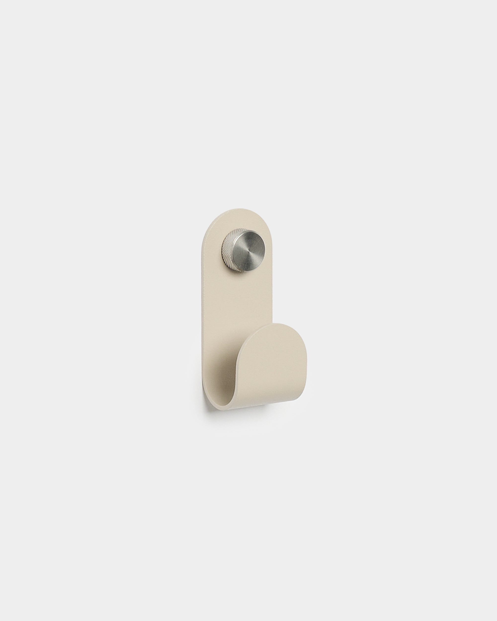WoodUpp Norr Single Hanger en beige, avec une forme courbée minimaliste et une finition en métal brossé, conçu comme accessoire pour les crochets muraux compacts Akupanel.
