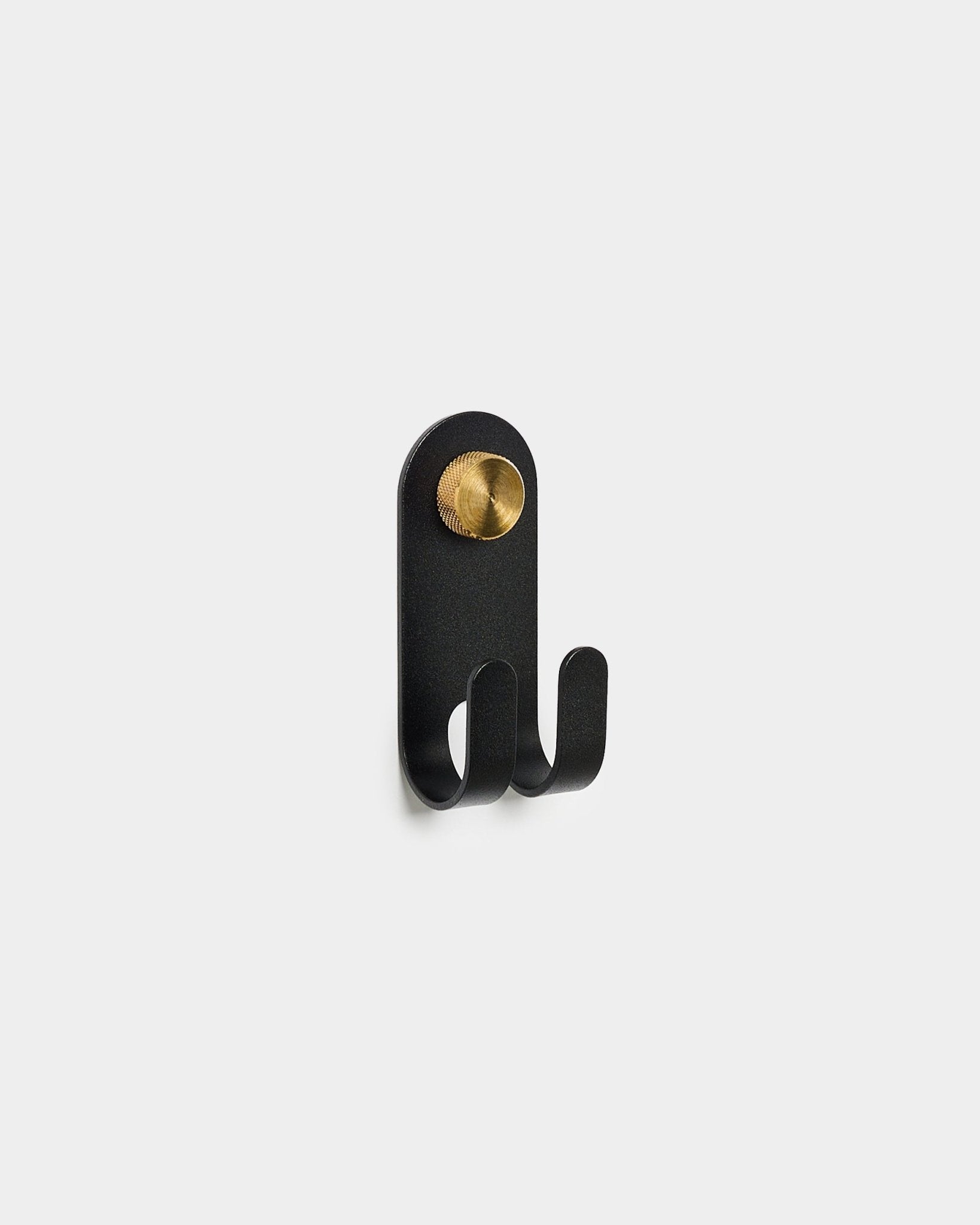 Le WoodUpp Norr Double Hanger en black, avec deux crochets et un détail rond en brass, est présenté sur un fond blanc uni.