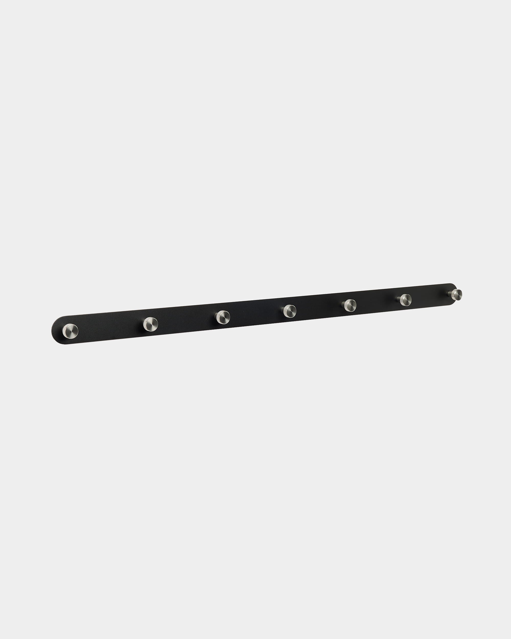 La patère WoodUpp Norr présente un design nordique black avec 7 crochets argentés, conçu pour compléter les panneaux acoustiques Akupanel dans une entrée ou un couloir.