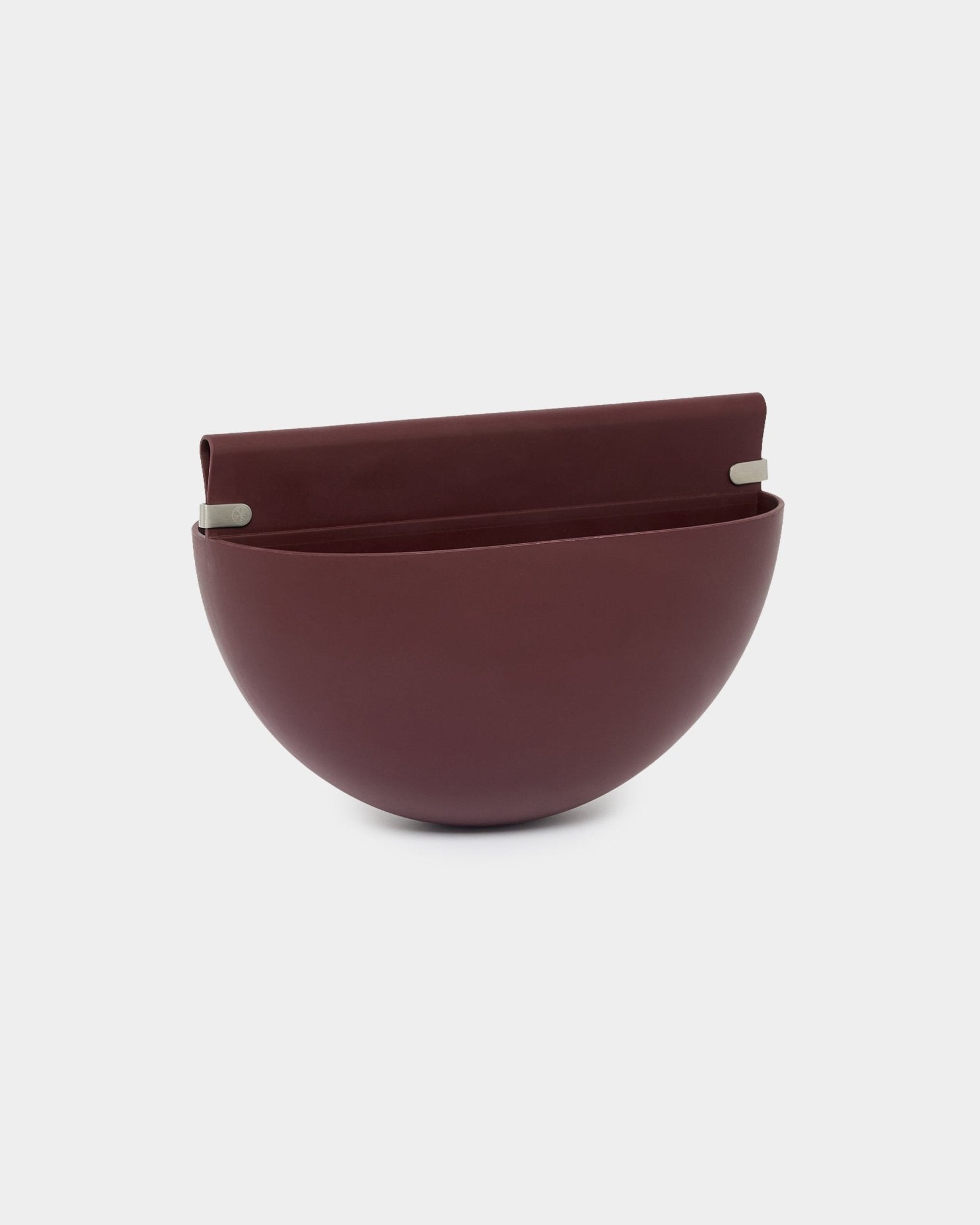 Le cache-pot WoodUpp Gro Soft Pocket / BM2 en Ox Red, d’une capacité de 4 L, présente une forme en demi-sphère, un dos plat et deux supports métalliques pour le montage sur des panneaux acoustiques.