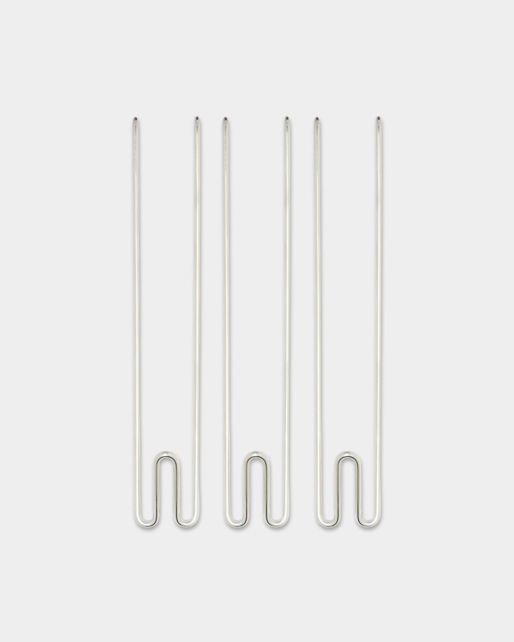 Trois accessoires Alva Wire Hook / BM1 de WoodUpp, longs crochets en steel inoxydable disposés verticalement sur un fond blanc uni.