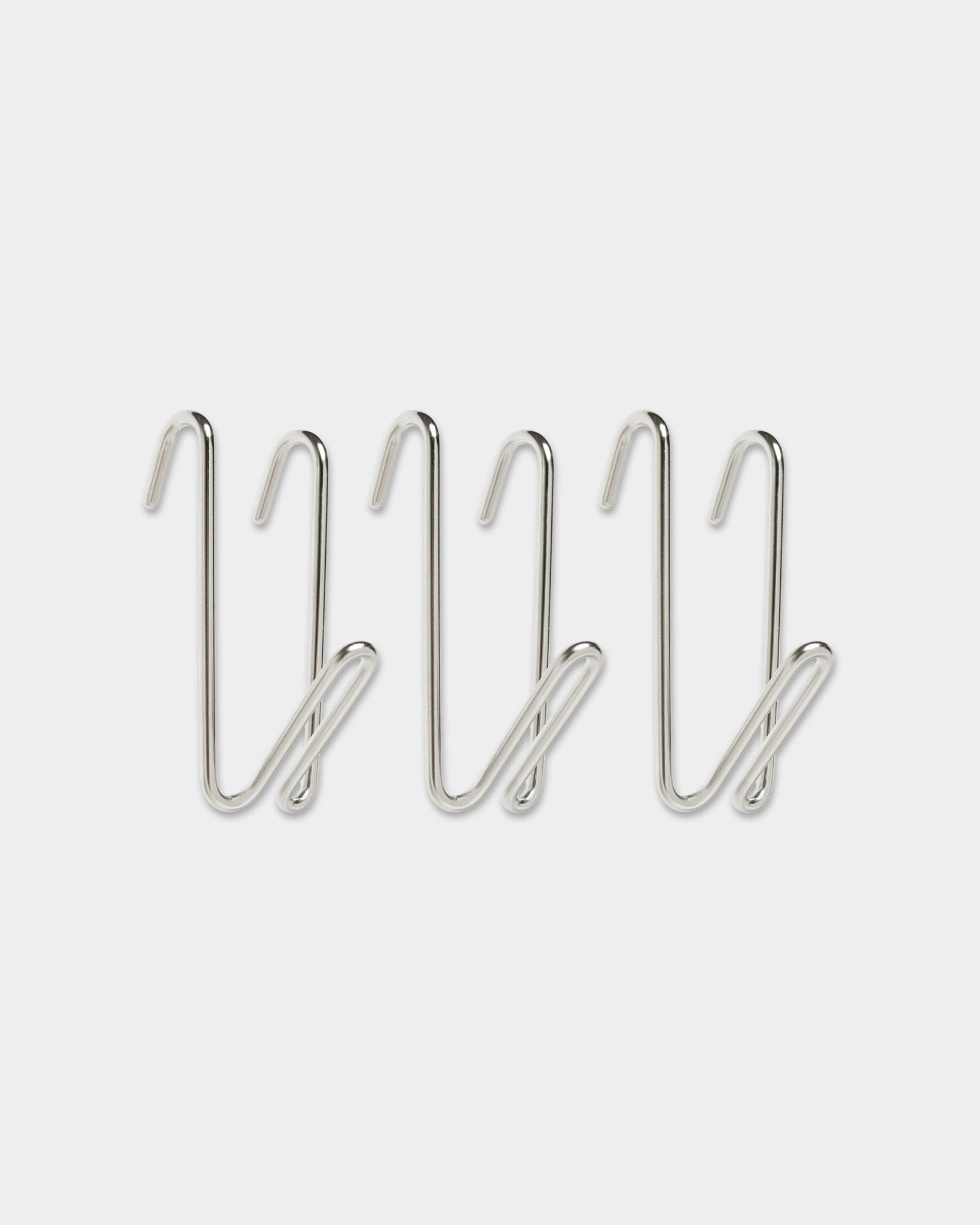 Trois patères filaires Alva / BM1, en acier inoxydable, format court de la collection CREATE de WoodUpp, au design en boucle, alignées sur une rangée sur fond blanc uni.
