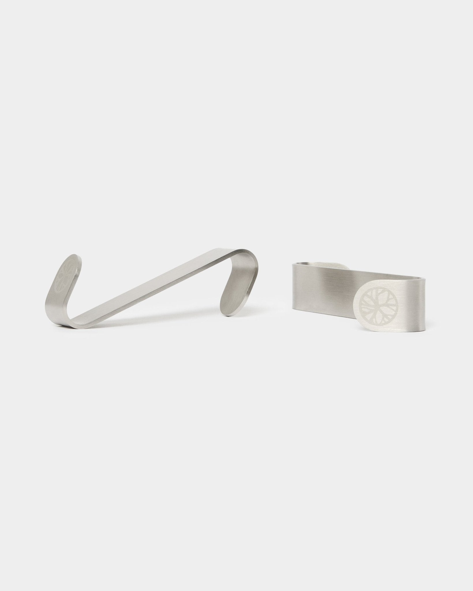 WoodUpp Alva S-Hook, pinces à billets BM1 et BM2, deux accessoires en acier inoxydable avec motifs de roue gravés, conçus pour des panneaux acoustiques en bois au style nordique.