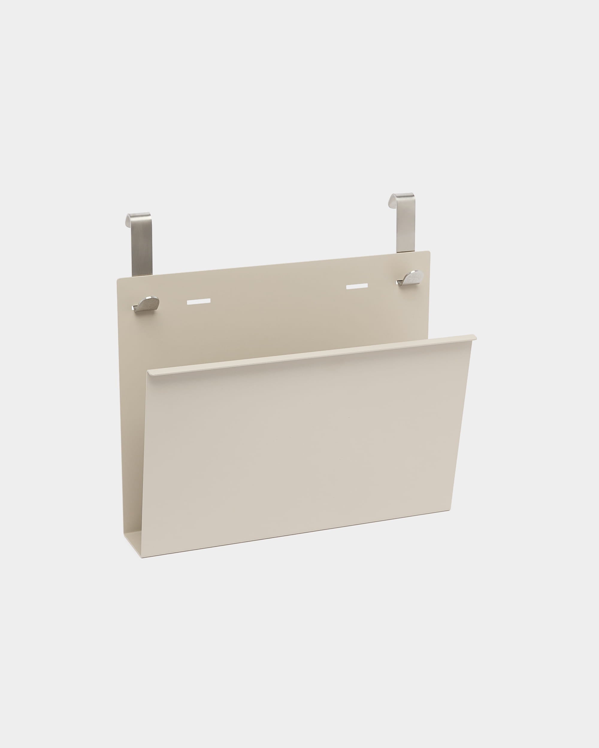 Le porte-revues Nell de WoodUpp est un support en steel thermolaqué beige, avec deux crochets argentés pour l’accrocher à des séparateurs de pièce acoustiques nordiques ou à des cloisons.