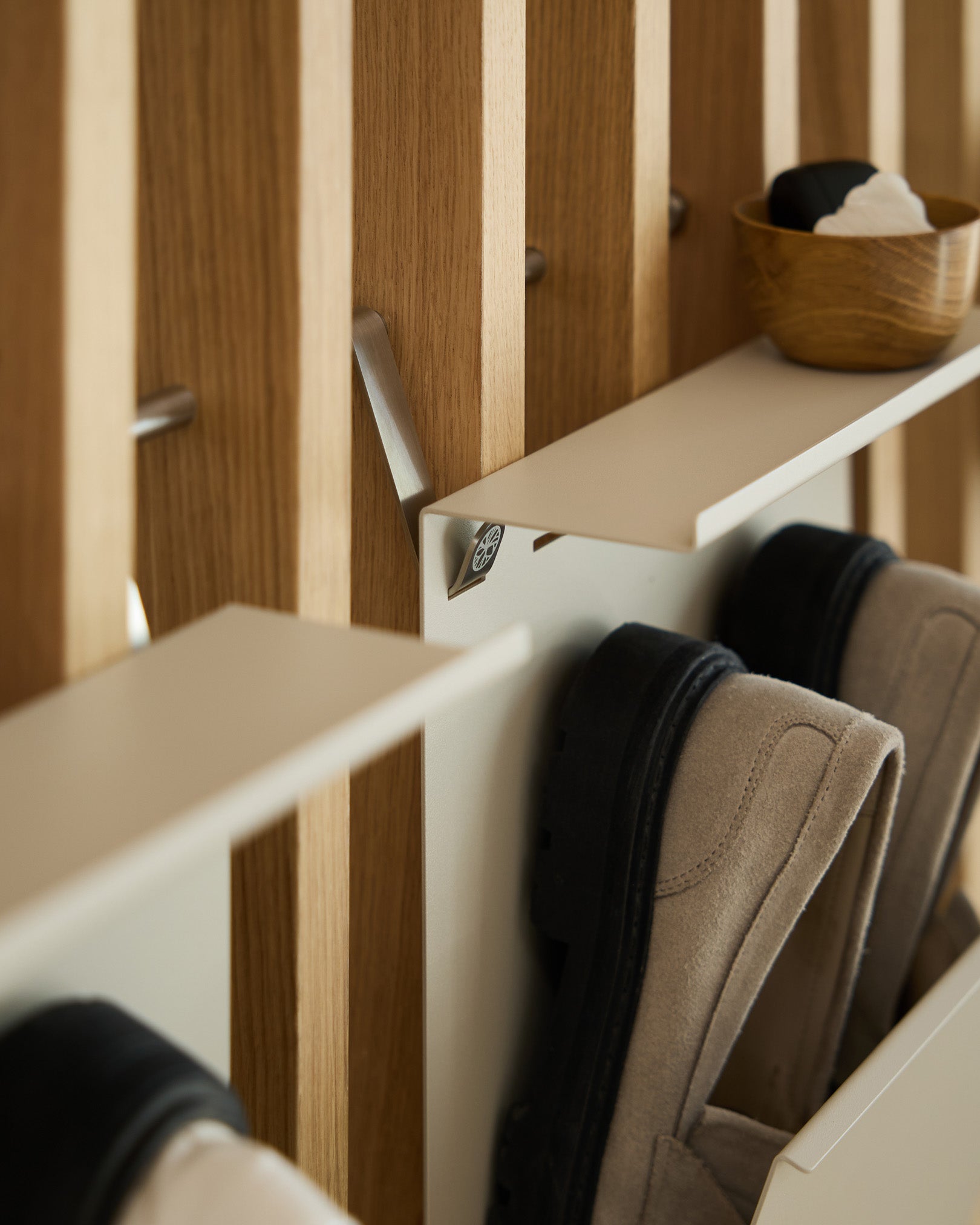 Range-chaussures minimaliste en beige en steel thermolaqué par WoodUpp, fixé sur un Panneau acoustique à lattes nordique, avec un small bol pour les clés placé au-dessus.