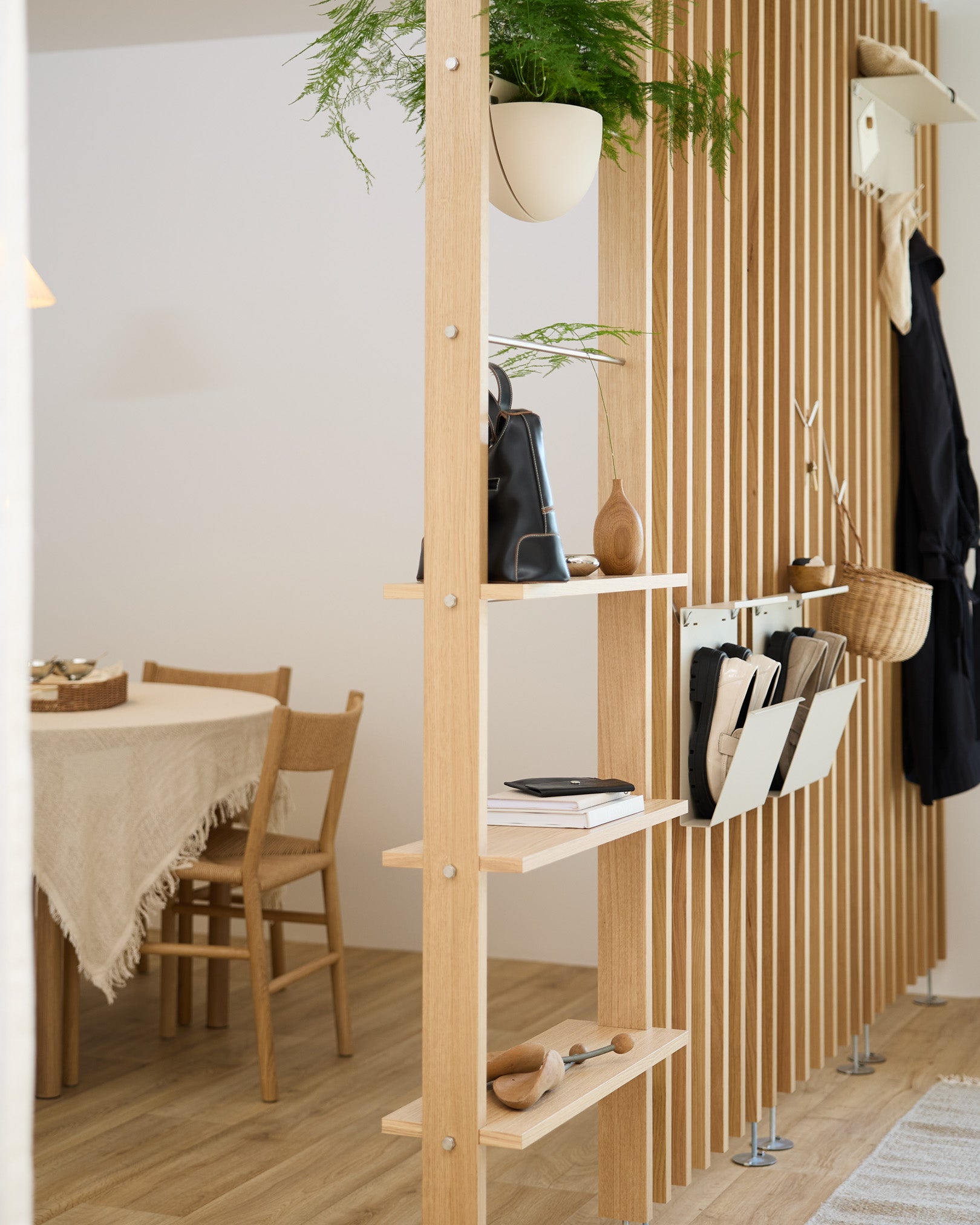 Des étagères ouvertes en bois séparent l’espace repas et mettent en valeur le rangement à chaussures Nell en beige de WoodUpp, pour un espace chaussures ordonné dans une maison nordique moderne.