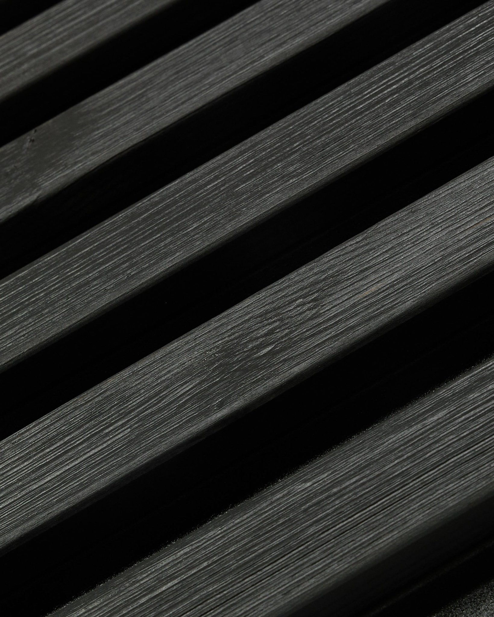 Panneau de façade extérieur Aluwood de WoodUpp, en Thermowood finition black, 240 x 45.1 cm, avec des lattes diagonales en épicéa nordique aux veines et aux ombres visibles.