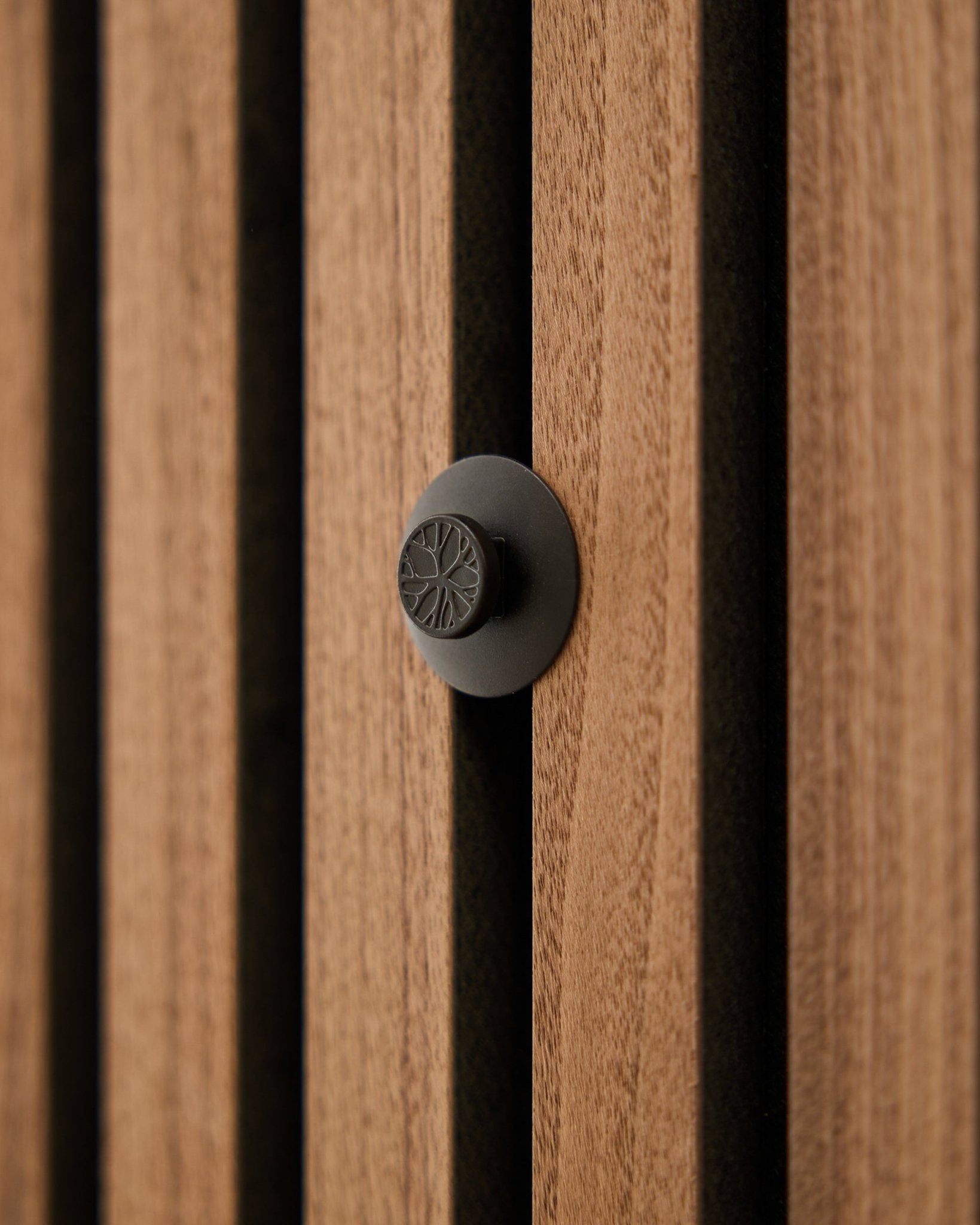 Nahaufnahme eines runden black Knaufs aus dem WoodUpp Dupps Original-Set, montiert an einer modernen vertical Akupanel Akustik-Holzleistenwand.