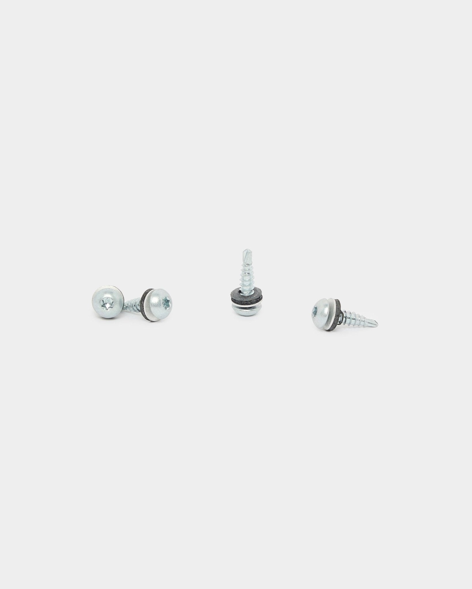 Trois vis arrière WoodUpp black (4.8x19, rondelle Ø10, TX20), utilisées pour l’installation de Panneau acoustique, sont disposées dans différentes directions sur un fond blanc.