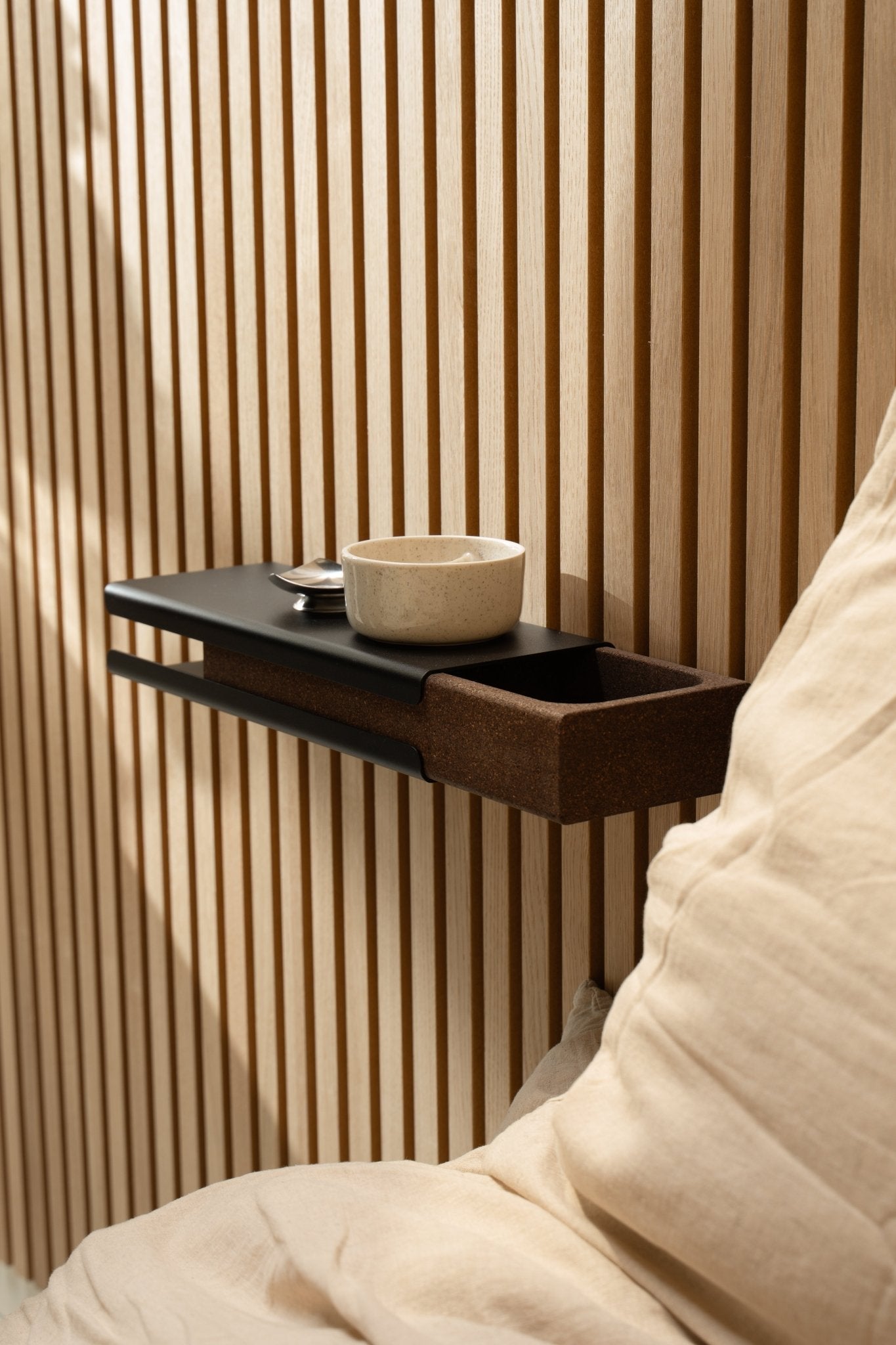 Étagère murale minimaliste avec un bol en céramique et le WoodUpp Norr Key Tray à côté d’un coussin beige et d’un Akupanel Panneau acoustique, éclairé par une douce lumière naturelle.