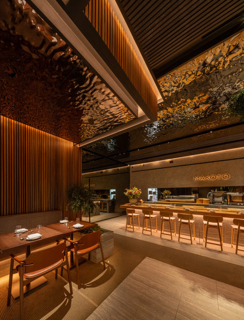 Restaurant interior with warm lighting, wooden furniture, bar seating, reflective ceiling, and Nordic-style Akupanel acoustic wood panels on the walls.