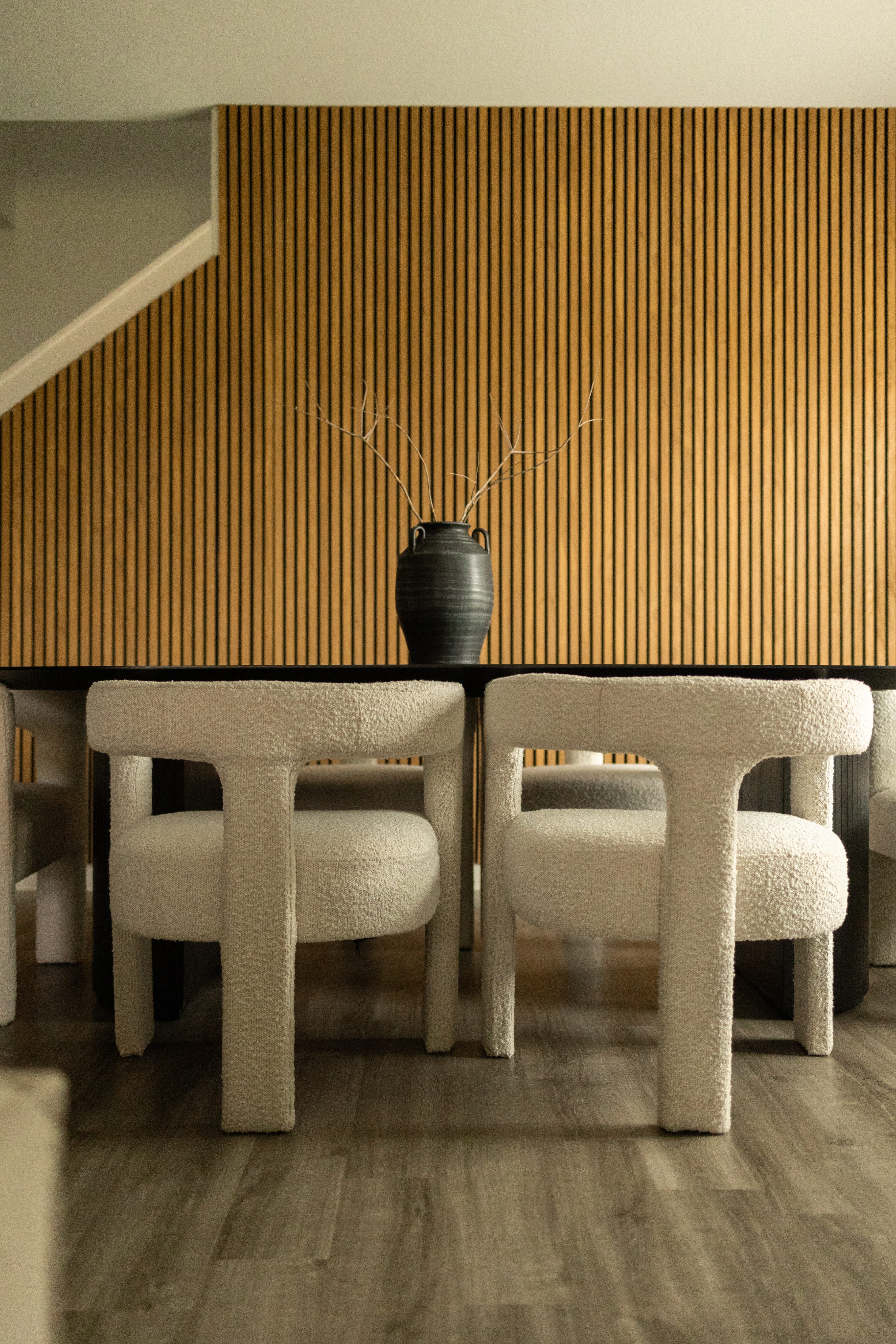 Akupanel wood slat acoustic wall panels behind table with chairs and black vase