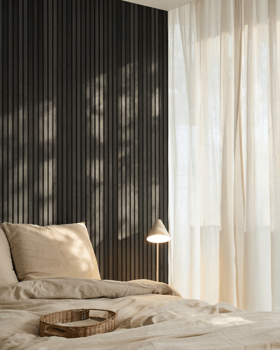Chambre nordique minimaliste avec un WoodUpp Akupanel Panneau acoustique en frêne Black, une literie beige, un plateau en osier et des rideaux voilés laissant entrer la lumière naturelle.